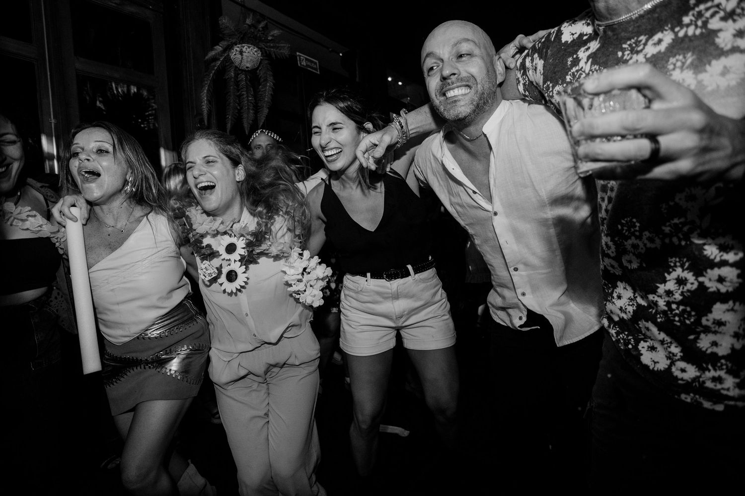 Black and white photo of a joyful group of friends dancing and laughing together at a lively nightclub event.