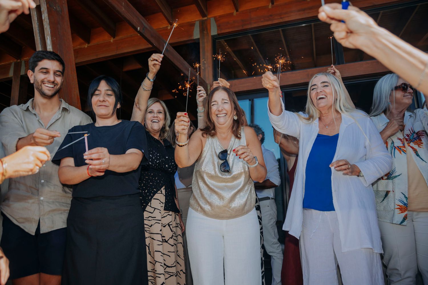 Group of joyful people celebrating with sparklers at an outdoor evening party event.