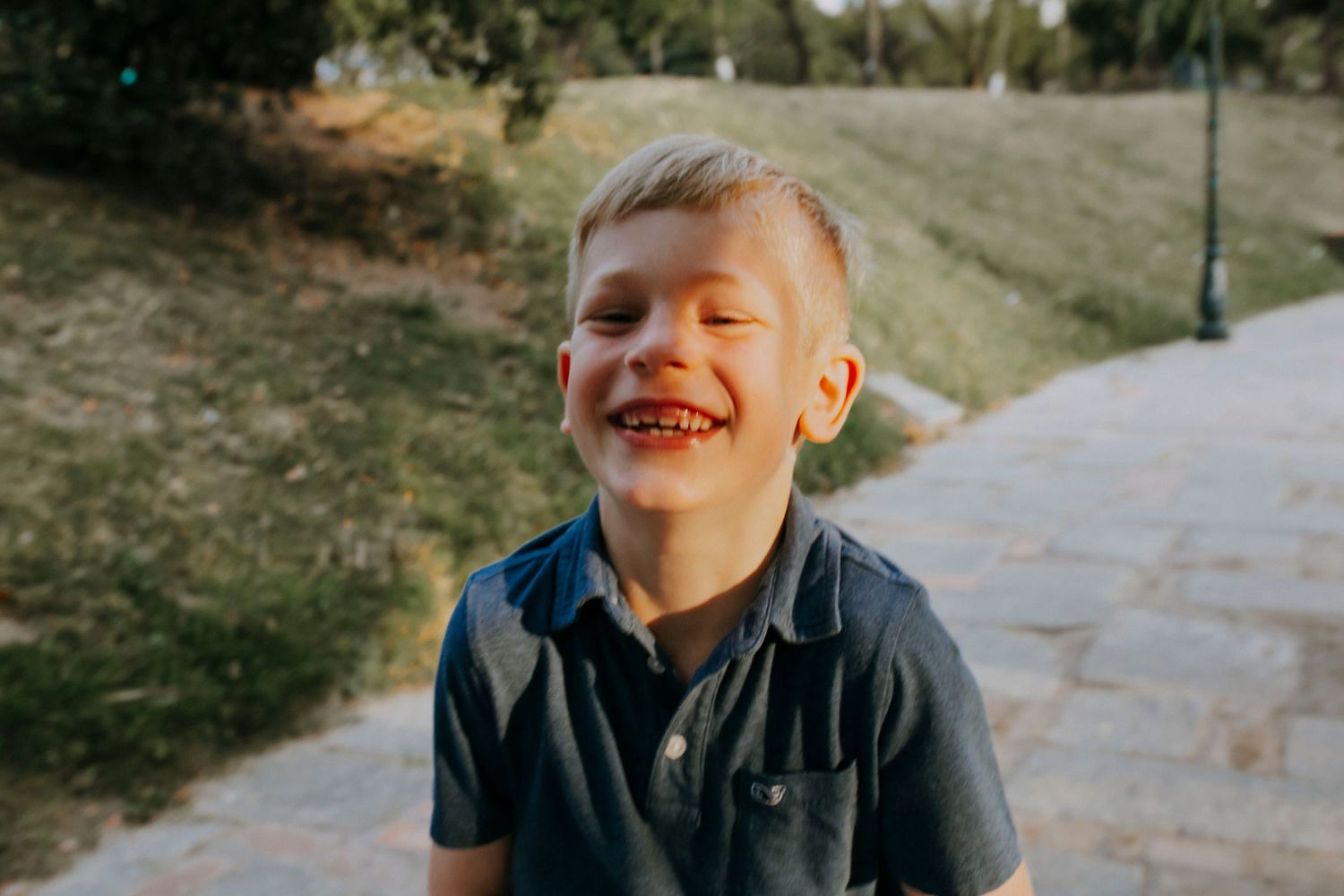 Candid portrait of laughing youth outdoors on sunny path.
