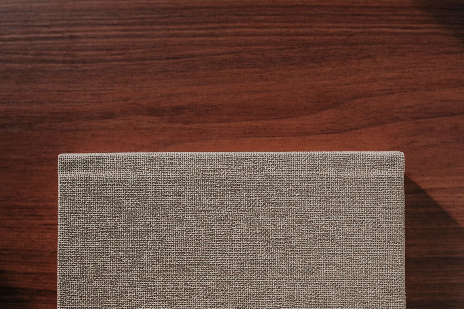 Close-up of a textured gray fabric album cover on mahogany wood surface.