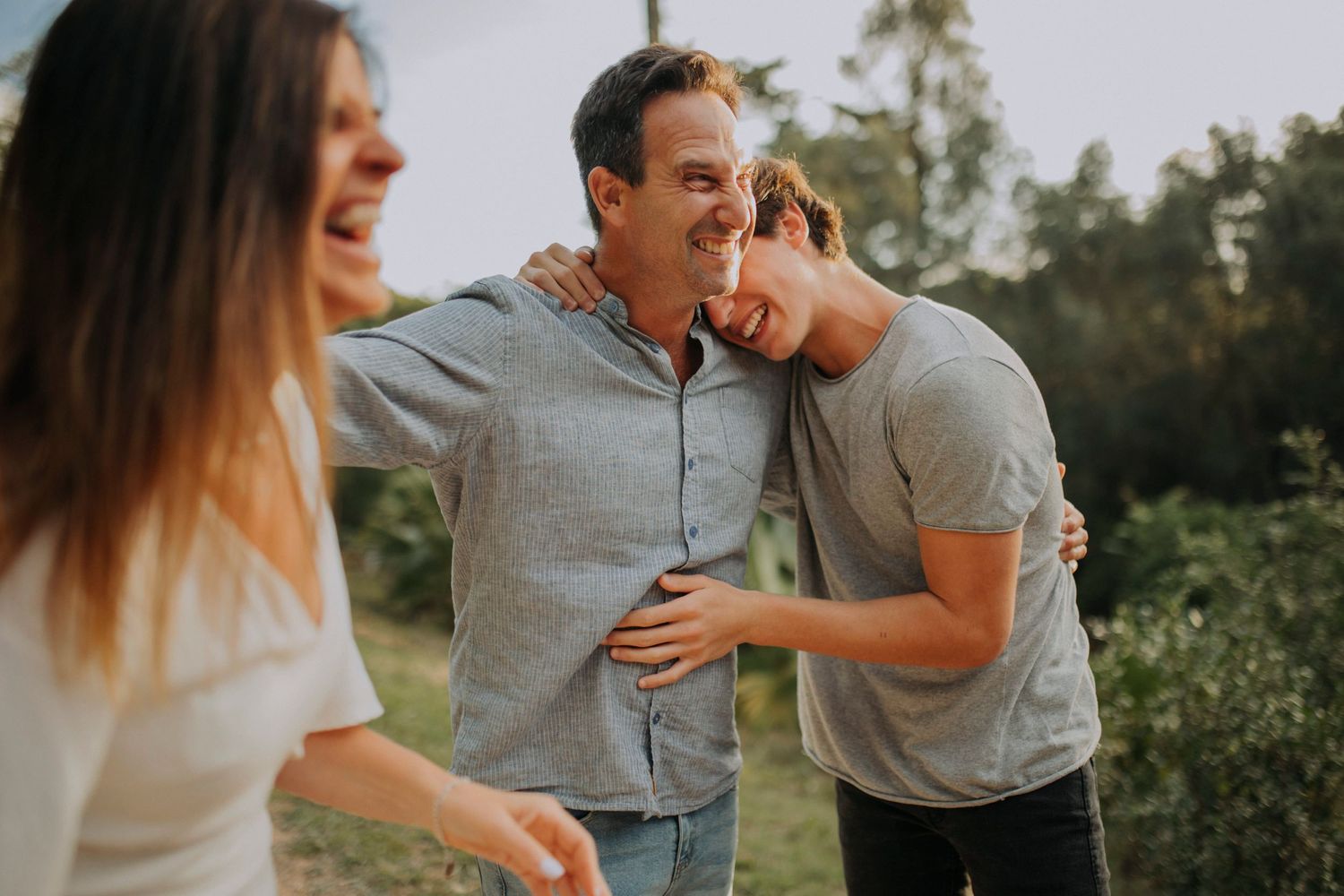 Family members embracing and laughing together in an outdoor setting.