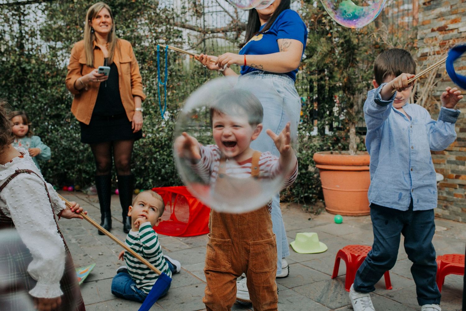 Children playing with bubbles in an outdoor garden setting during a fun party activity.