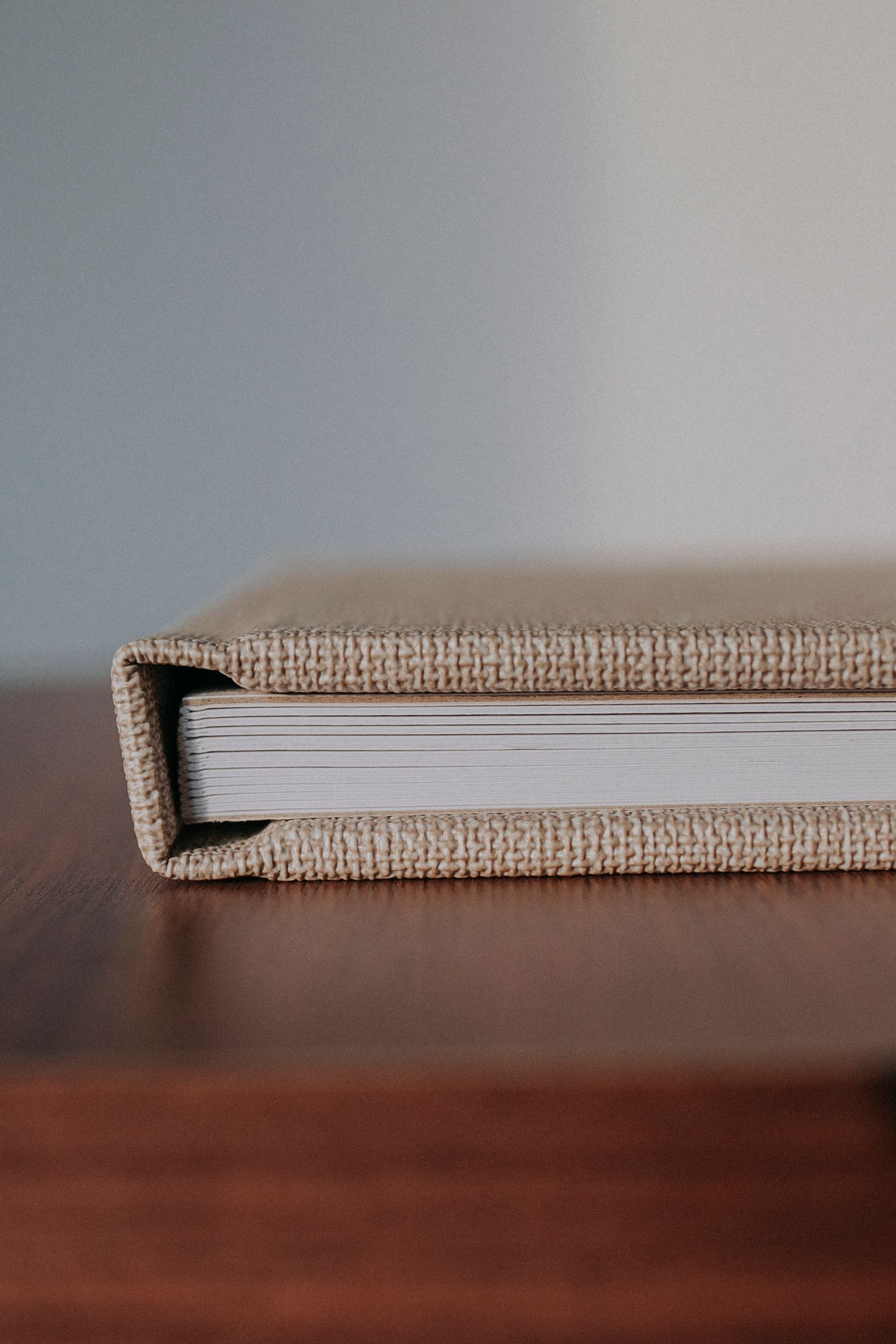 Close-up detail of book binding showing textured beige fabric cover and white pages.