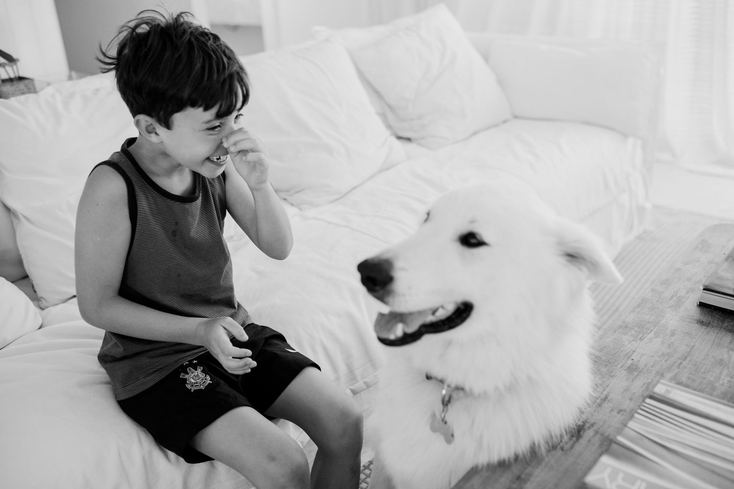 A child and a fluffy white dog sharing a sweet moment on a couch.