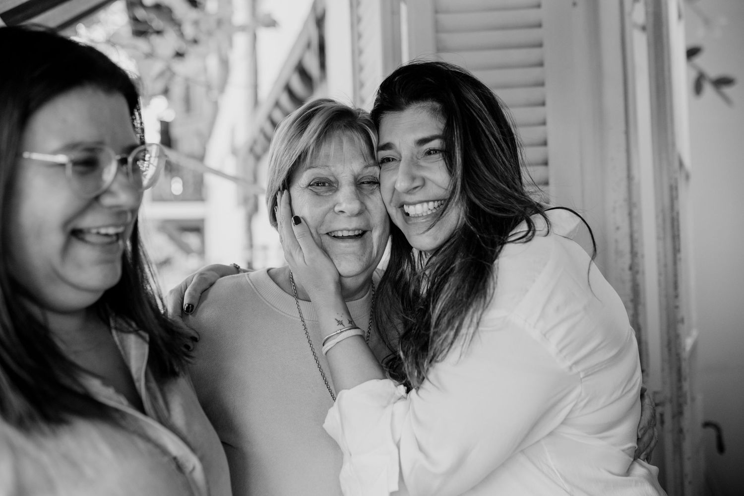 Three friends laughing and having fun together in black and white candid photo.
