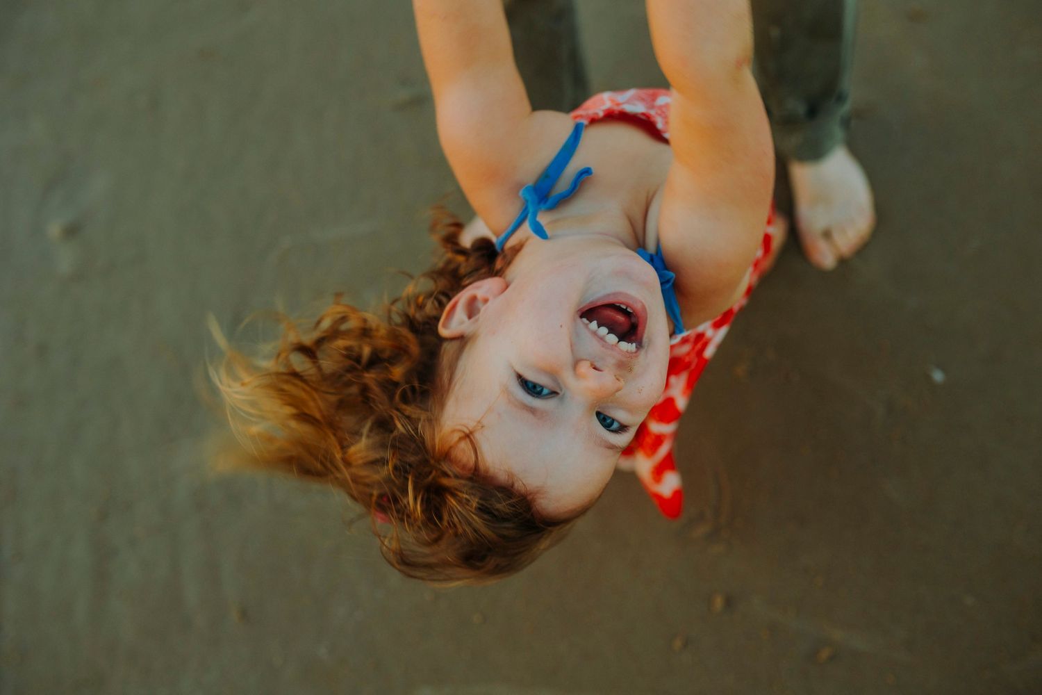 Upside down portrait shot with playful expression against dark background.