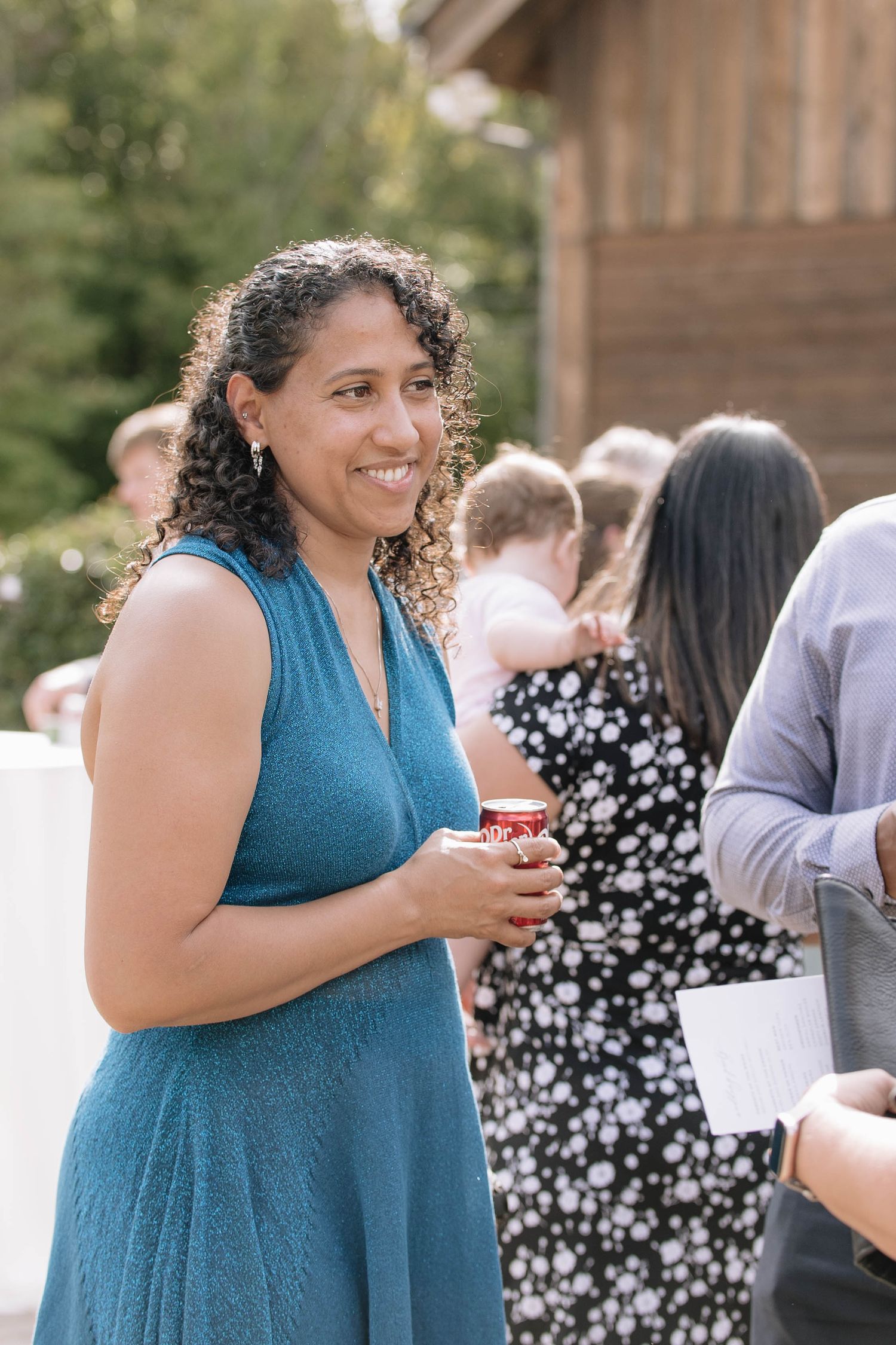 Guest in teal dress enjoys outdoor wedding celebration.
