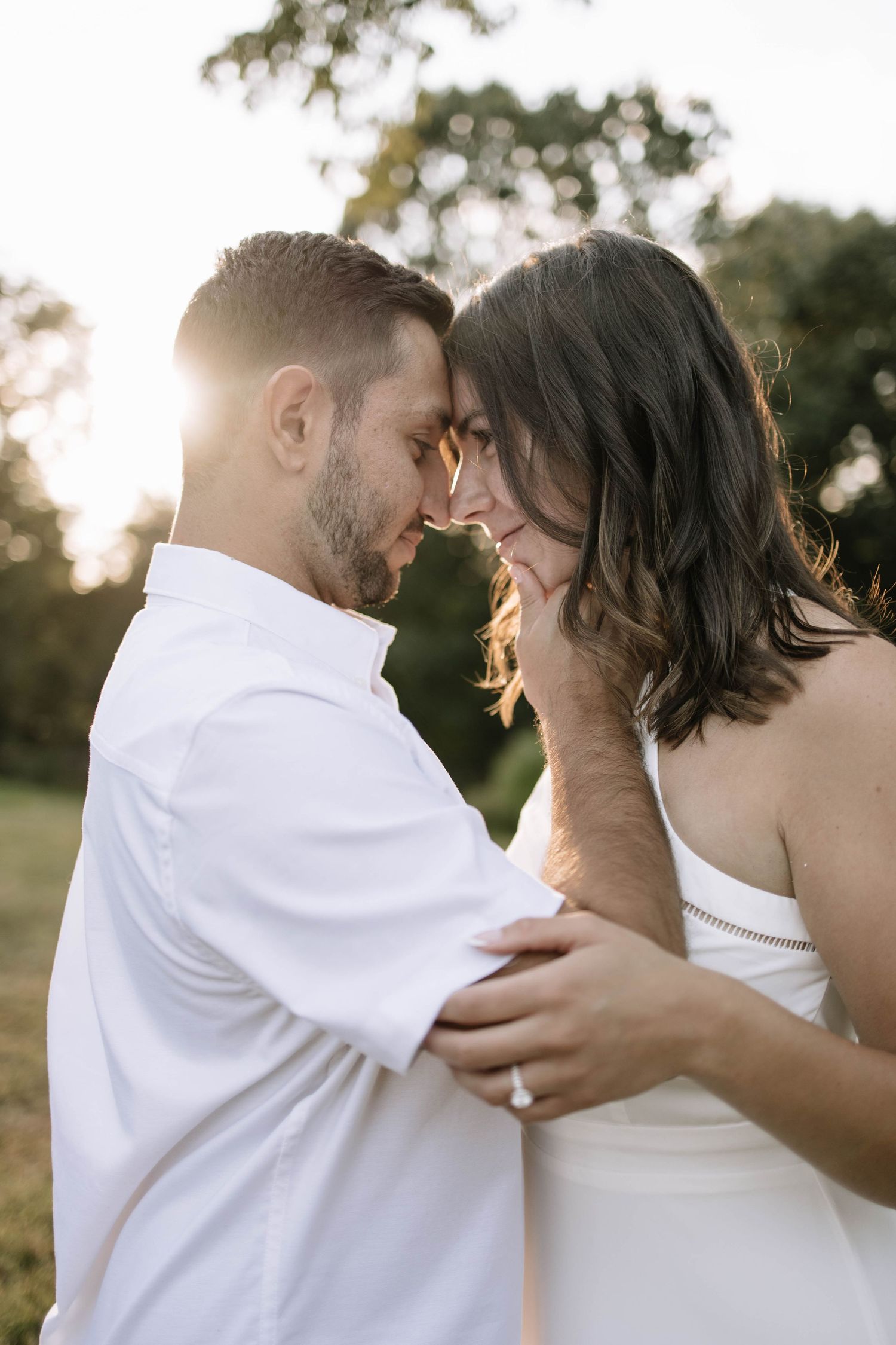 Intimate couple shares tender moments during sunset photoshoot in a park setting.