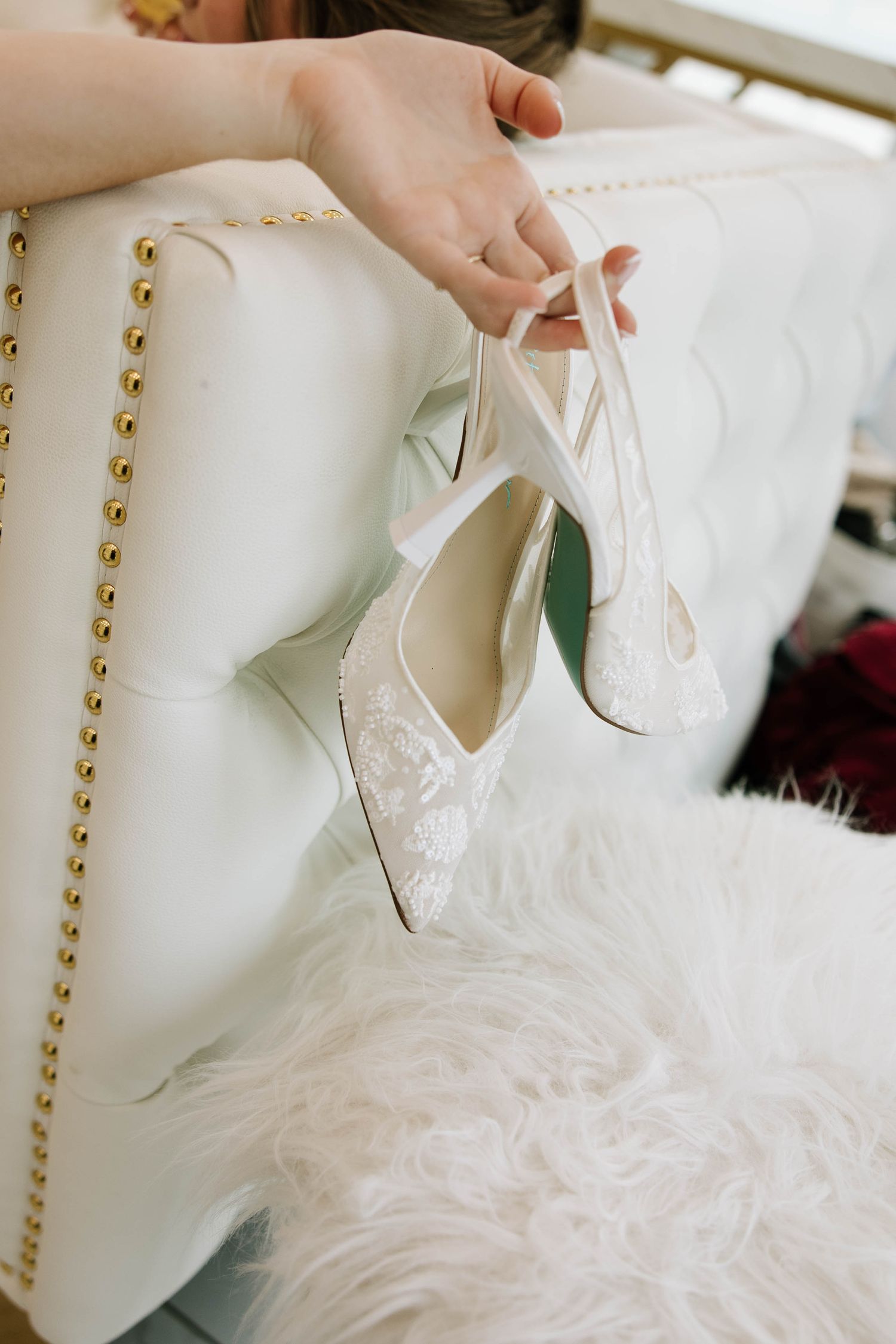 Close-up of delicate white bridal shoes with lace details.