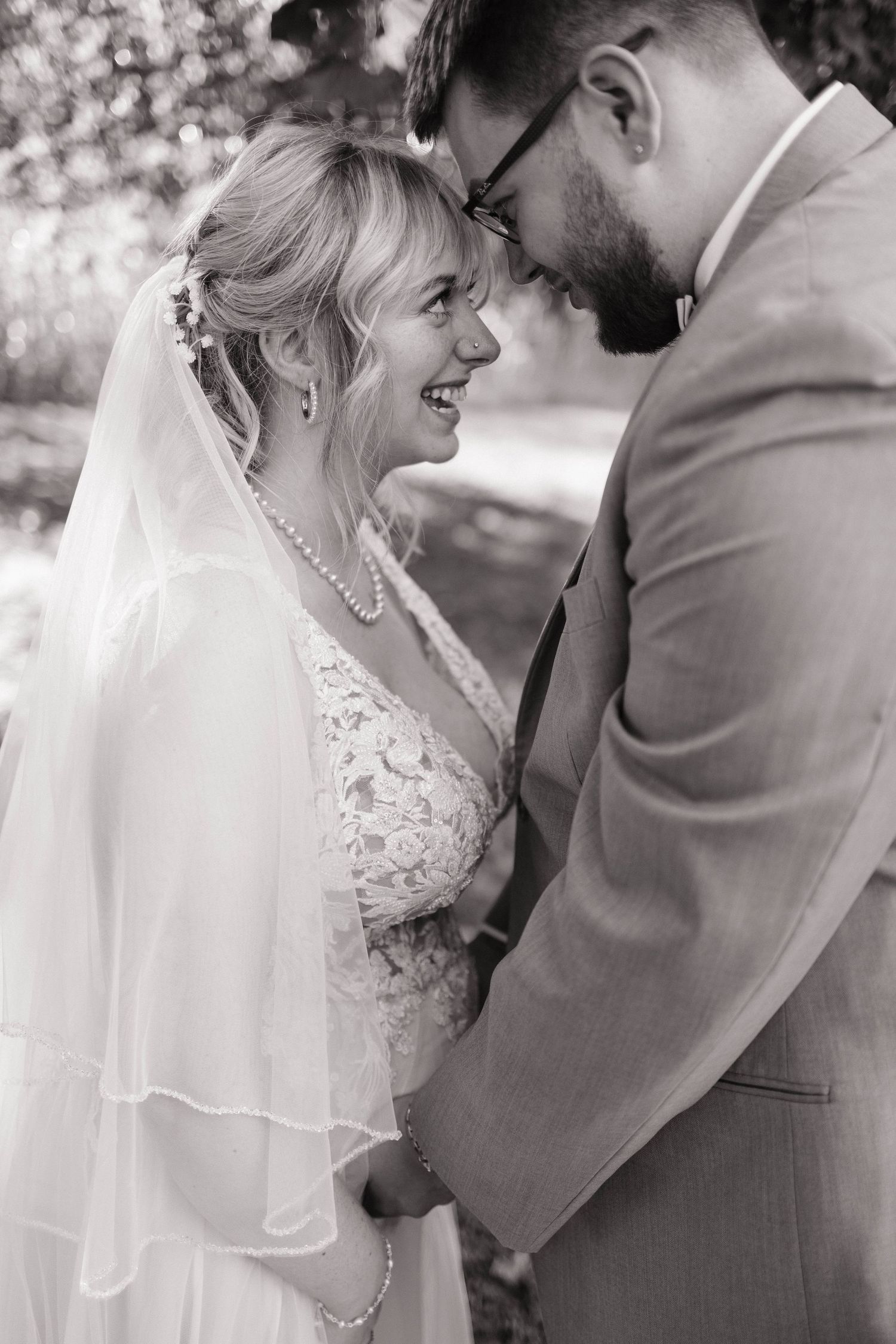 Black and white intimate wedding portrait showing tender moment between newlyweds.