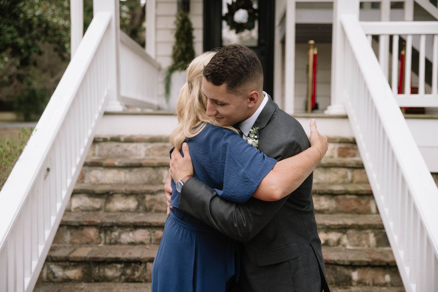 An intimate embrace shared on stone steps with white railings during a wedding celebration.