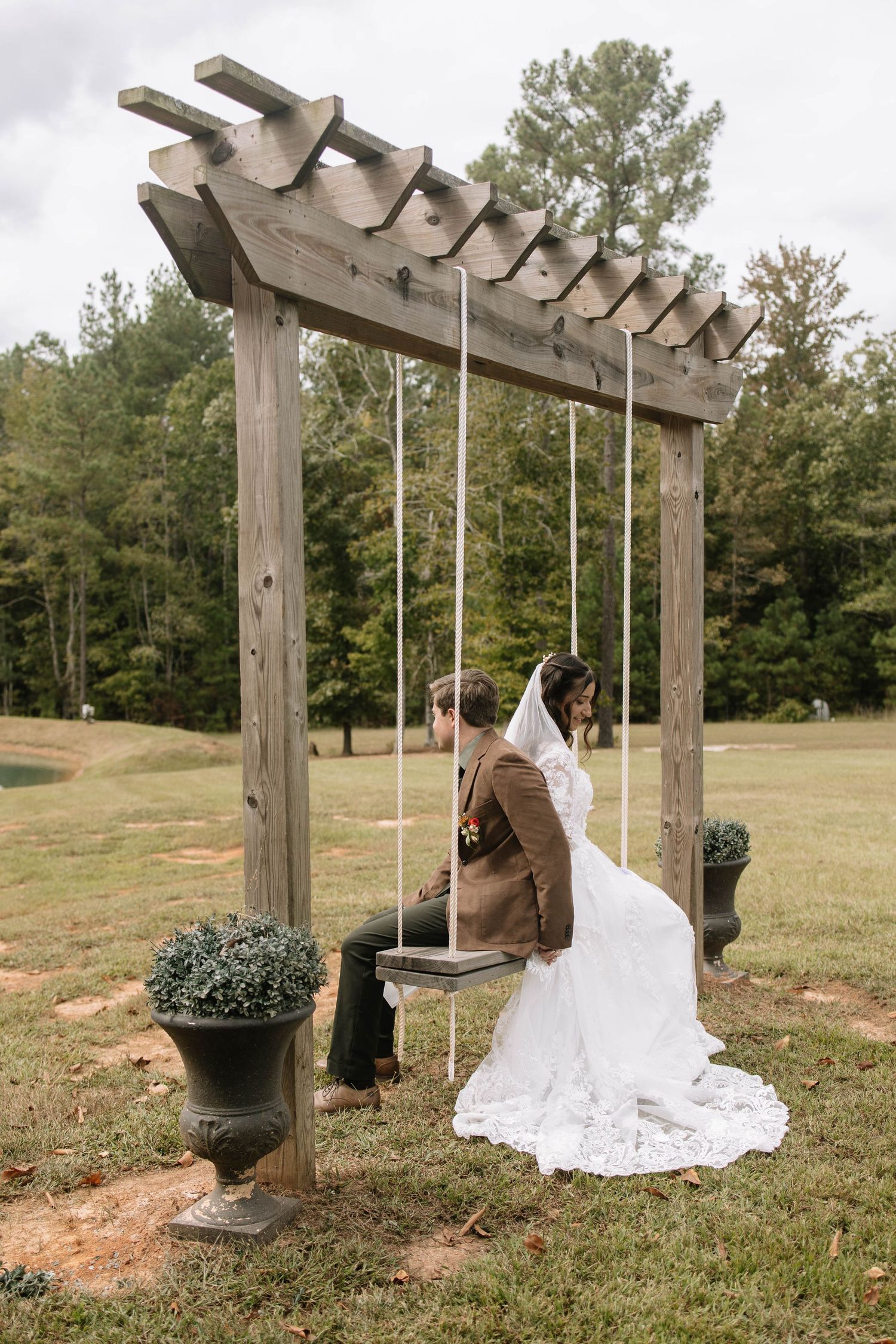 Wooden pergola swing decorated for a wedding ceremony in an outdoor field setting.