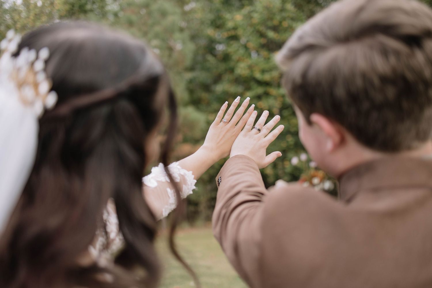 A couple shares their first look moment during an outdoor wedding photoshoot on a grassy hillside.