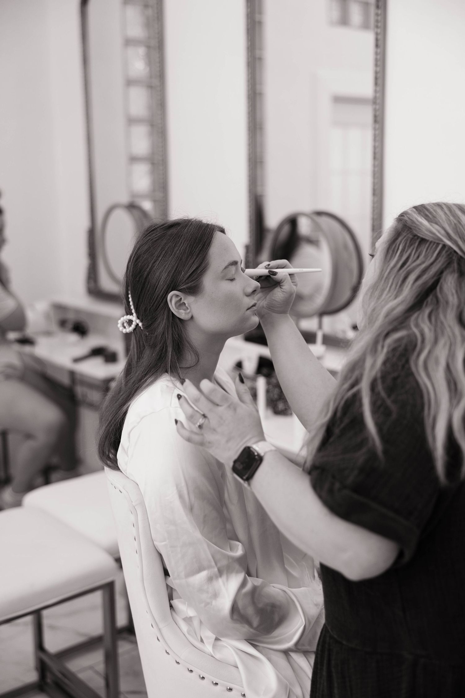 Getting ready scene with makeup application in black and white photography.