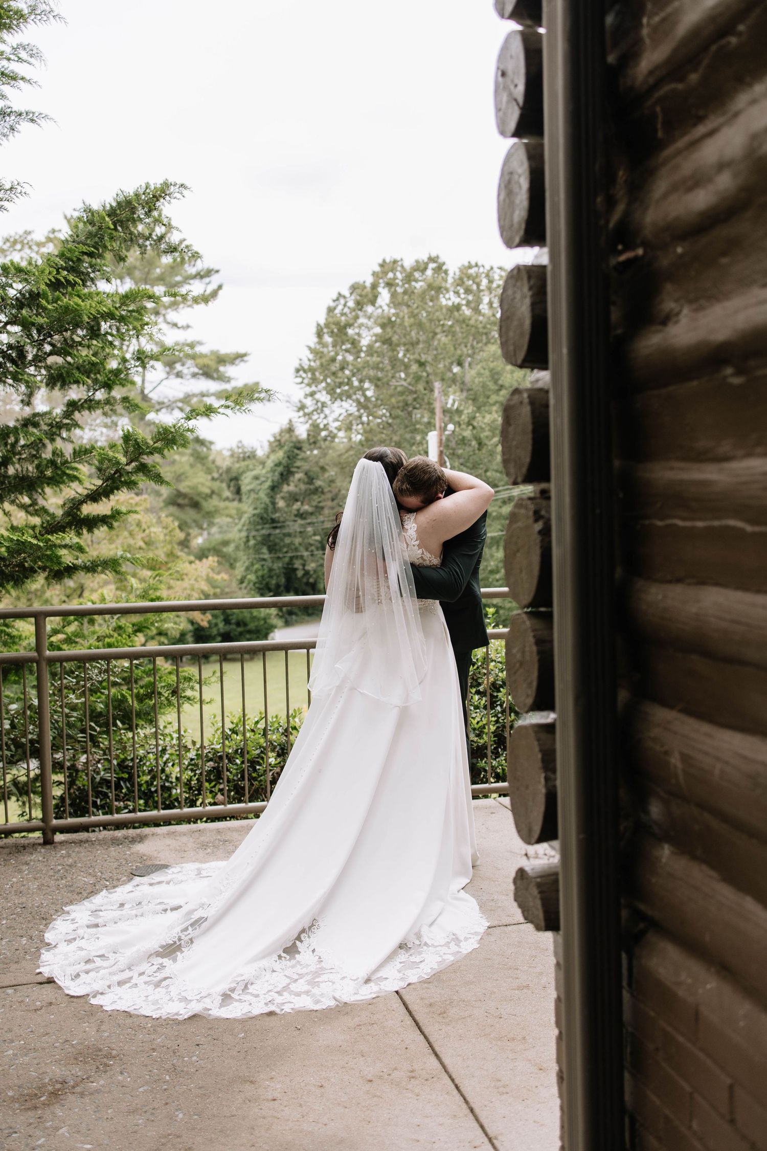 Wedding dress with long train photographed on a rustic cabin porch with scenic backdrop.