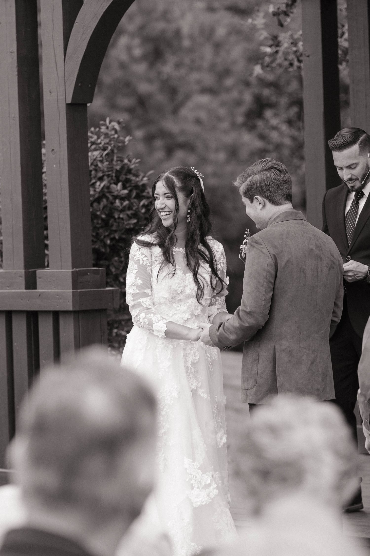 Couple embraces under wooden pavilion during wedding ceremony.
