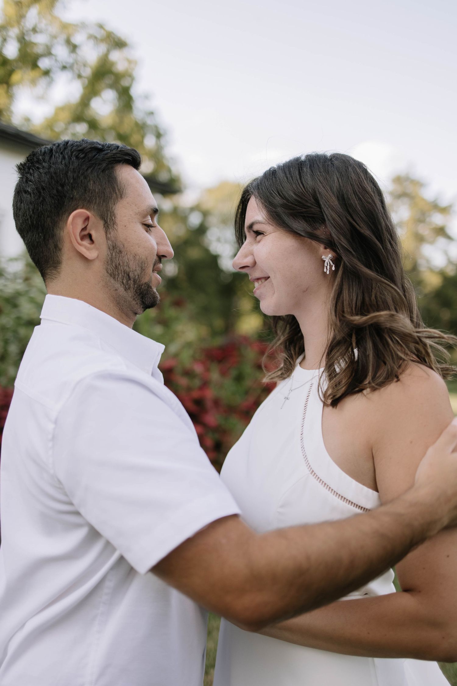 Close-up shots of a couple in white sharing tender moments outdoors.