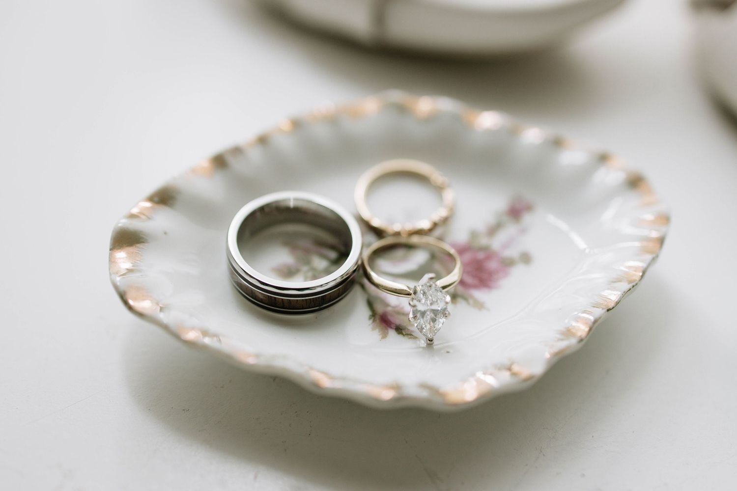 Wedding rings displayed on vintage porcelain dishes with delicate patterns.