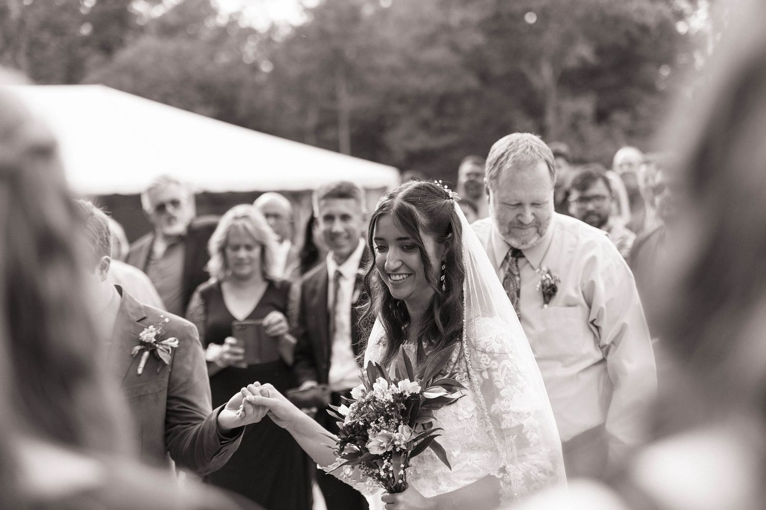 Wedding ceremony guests watching and smiling in black and white.