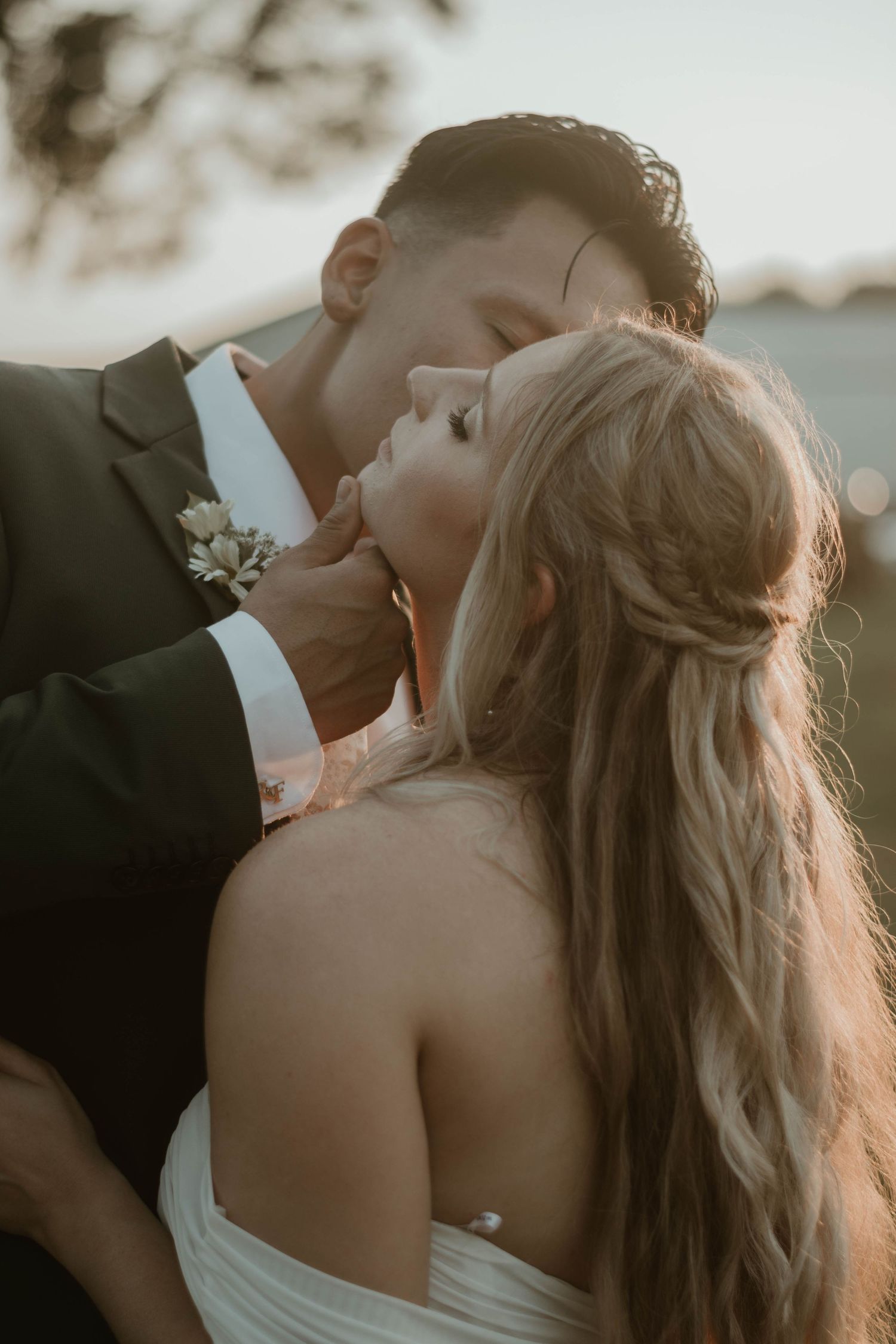 Romantic sunset moment between newlyweds in formal wedding attire.