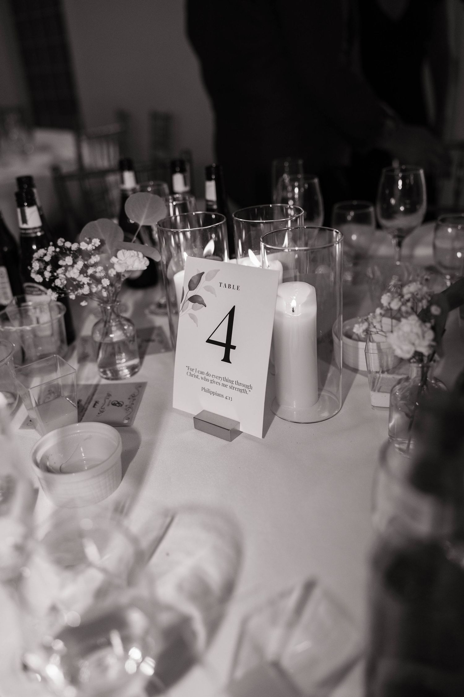 Wedding reception table settings with table numbers, wine glasses, and white linens.