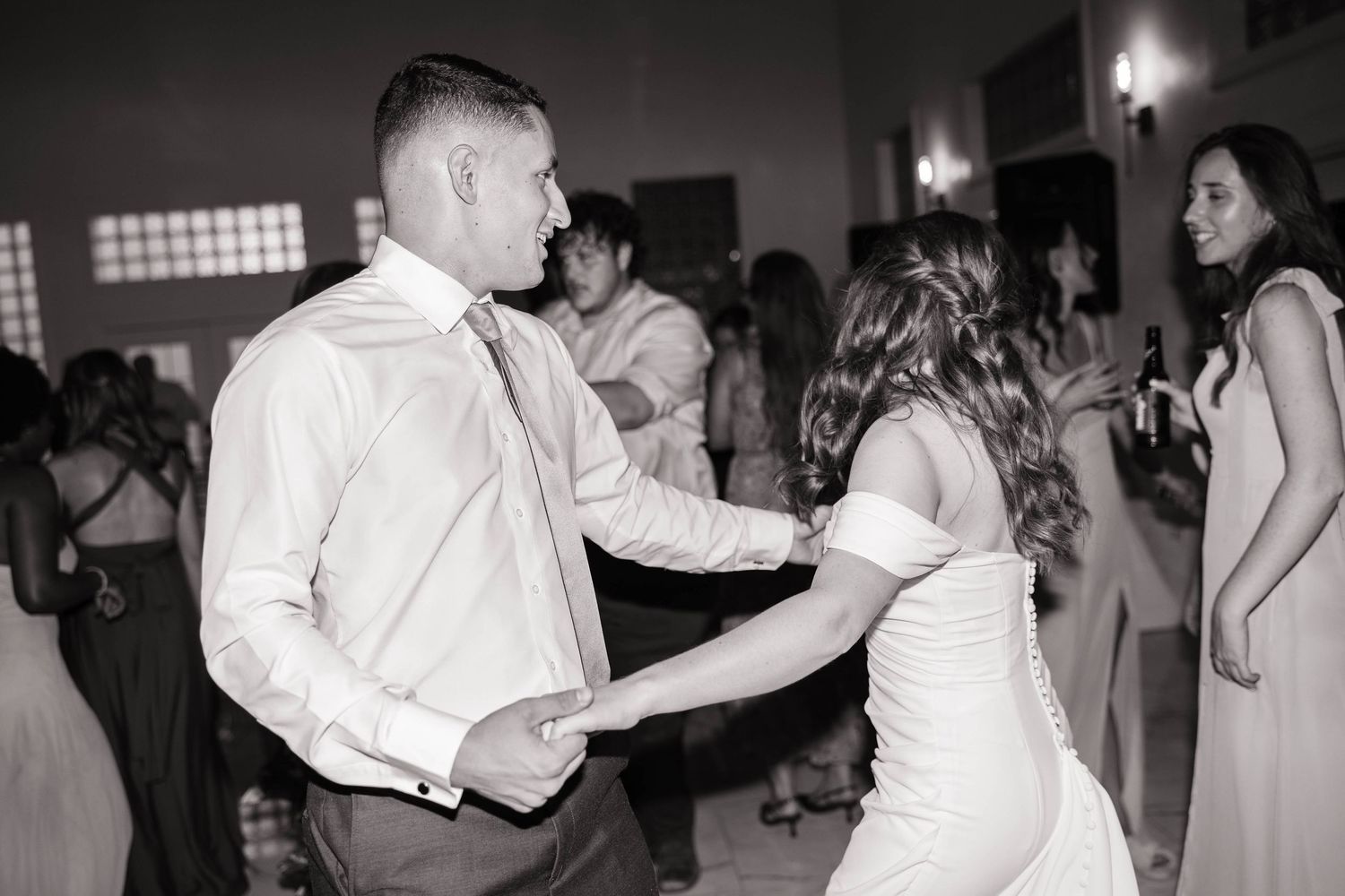 Wedding guests dancing and celebrating on the dance floor at an evening reception.