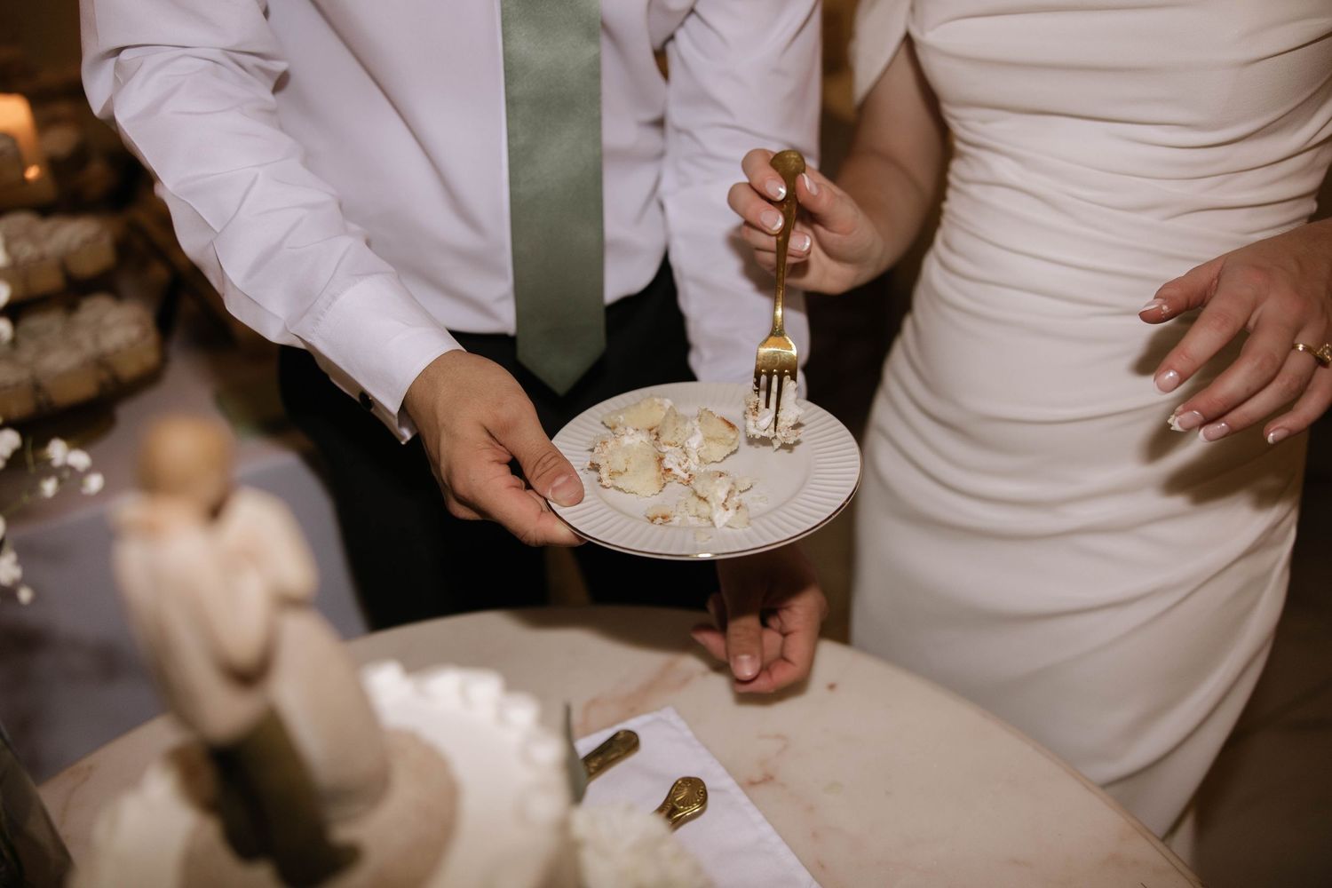 Newlyweds cut their elegant white wedding cake together during the reception.