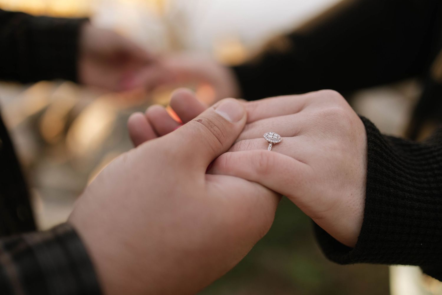 Close-up of hands holding each other tenderly against a dark background.