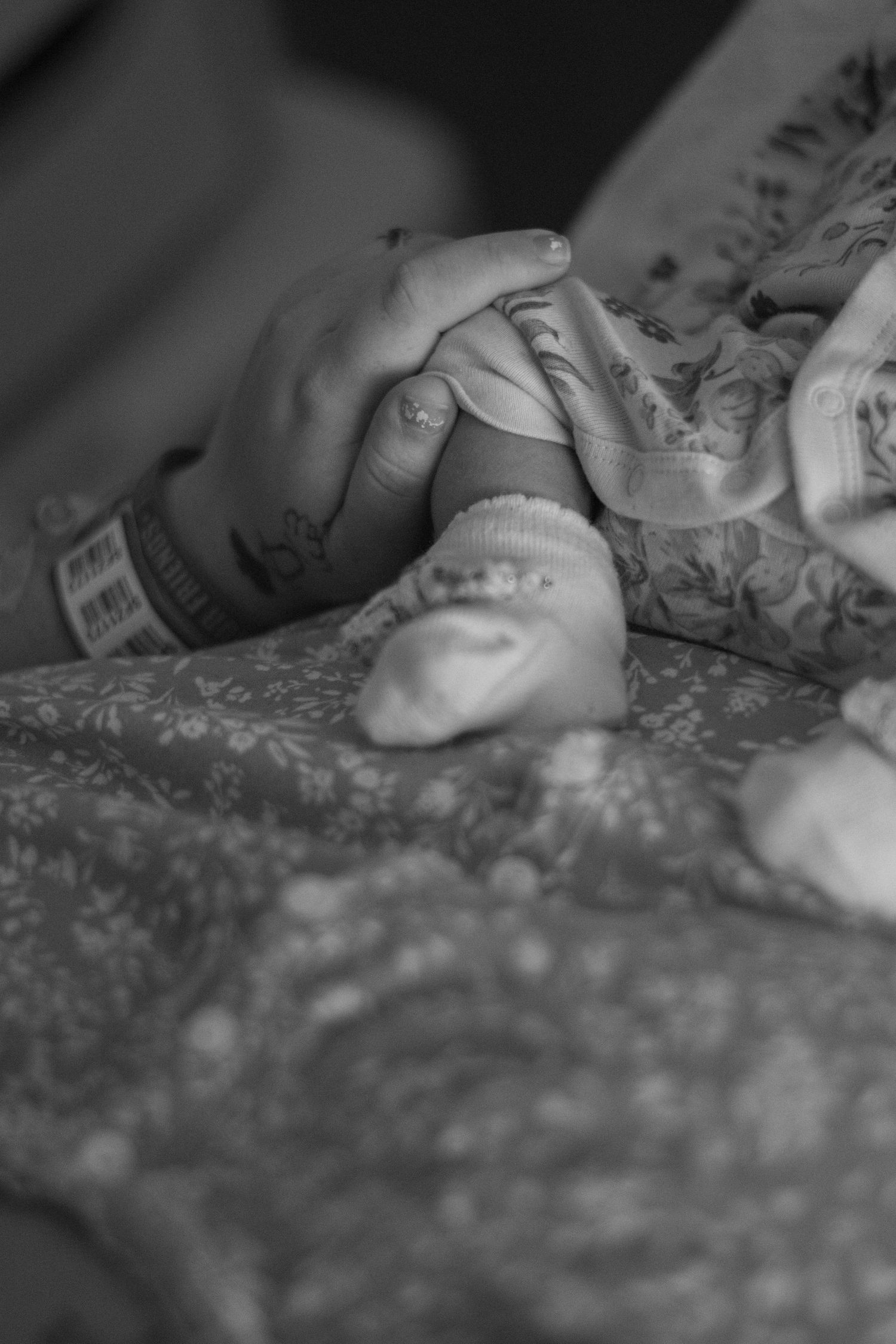 Close-up black and white shot of tattooed hands gently touching.