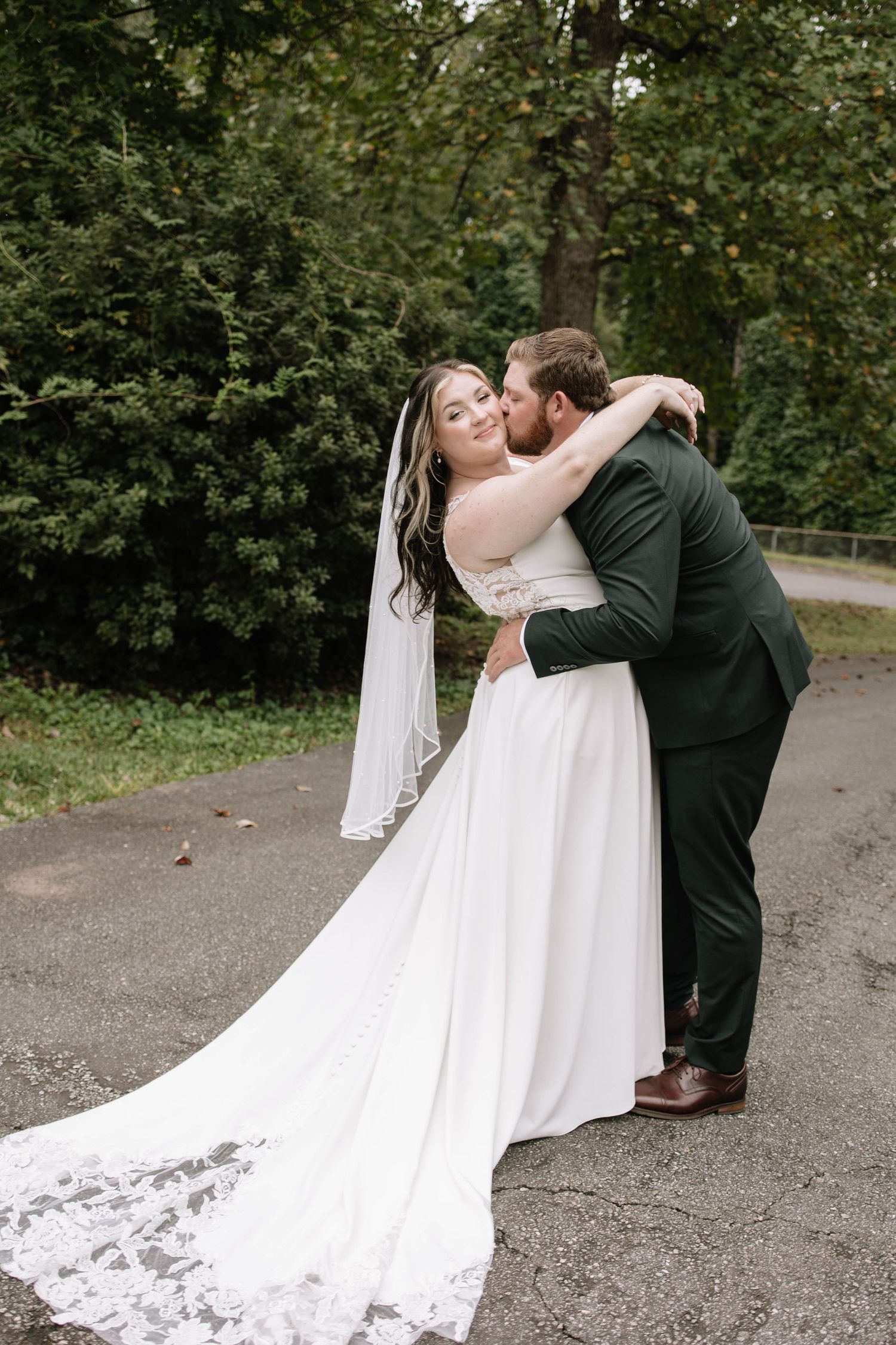 Wedding couple shares intimate moments in a series of candid photos on a gravel path surrounded by trees.