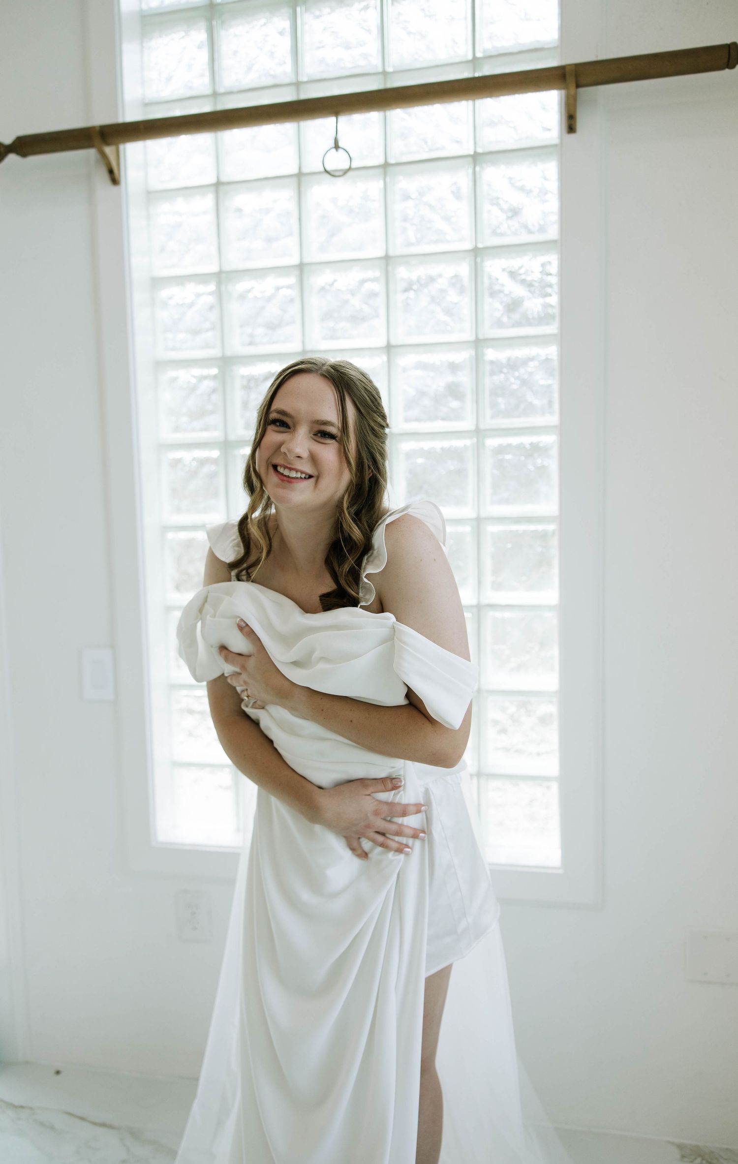 A series of intimate getting ready moments showing someone wrapped in a white sheet in a bright room with windows.