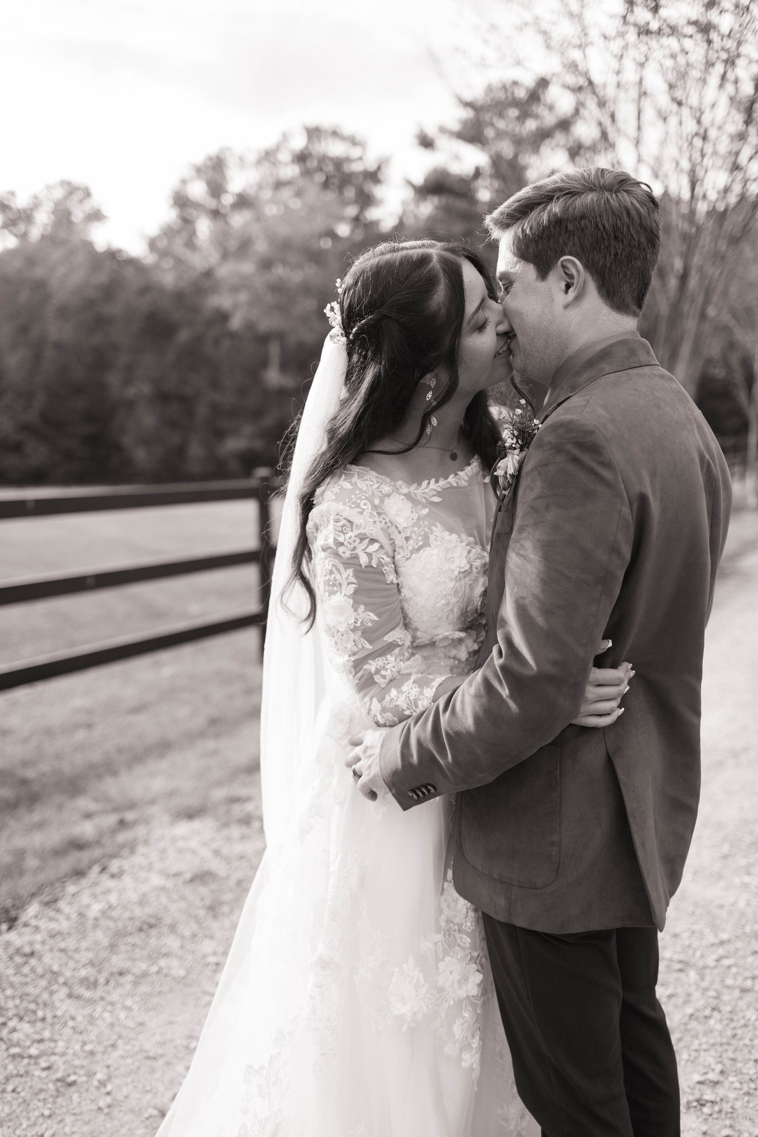Black and white wedding photo capturing an intimate moment between newlyweds outdoors.