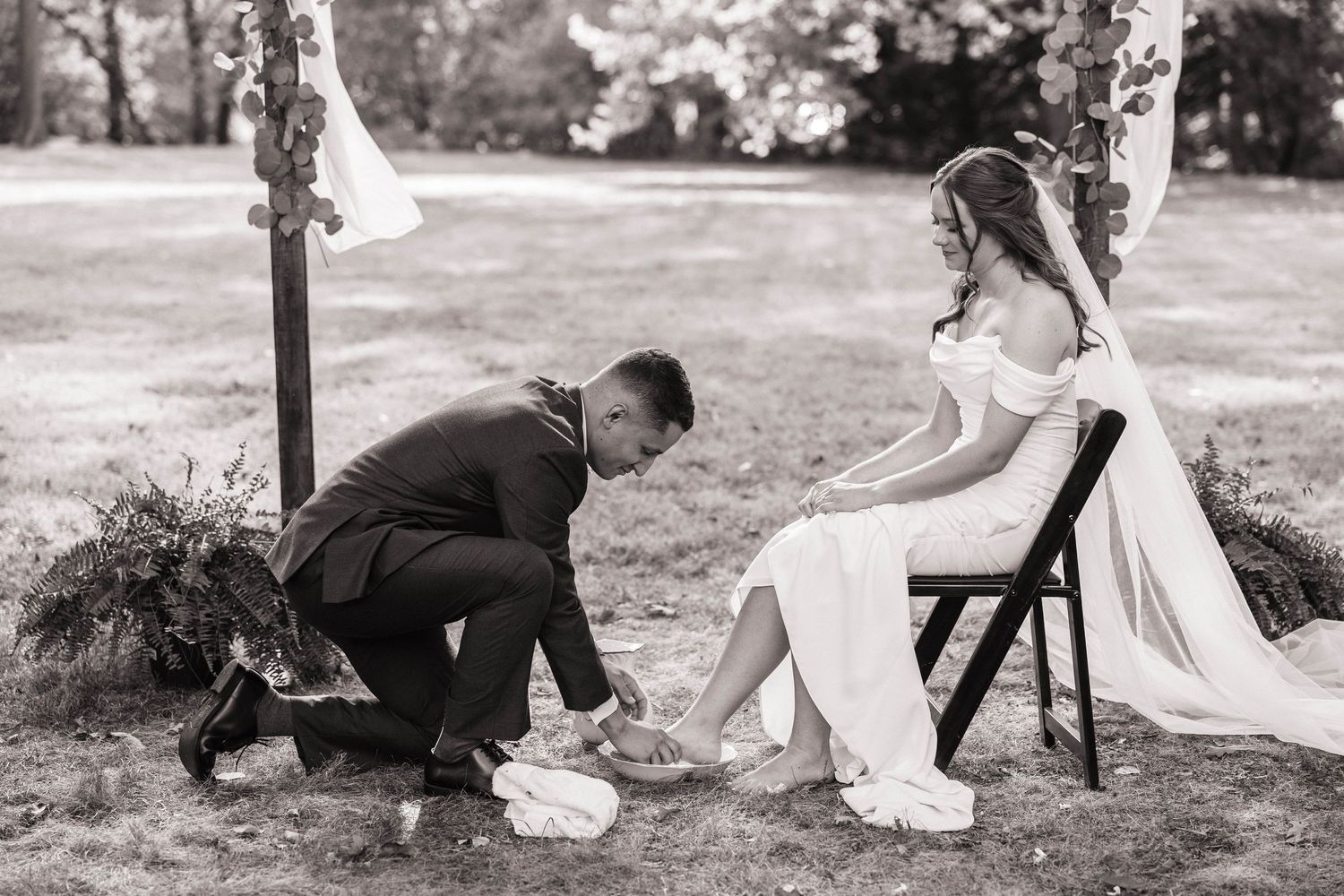 Playful wedding moment captured during traditional garter toss at outdoor ceremony.