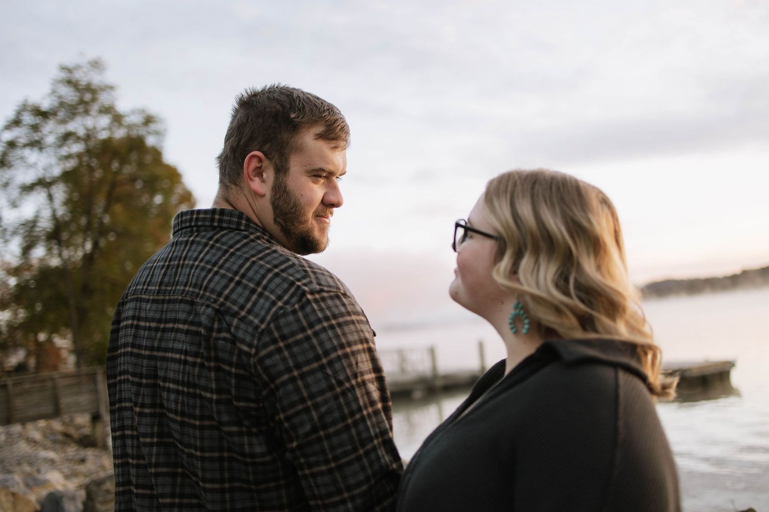 A couple enjoying a tender moment by the lake during golden hour.
