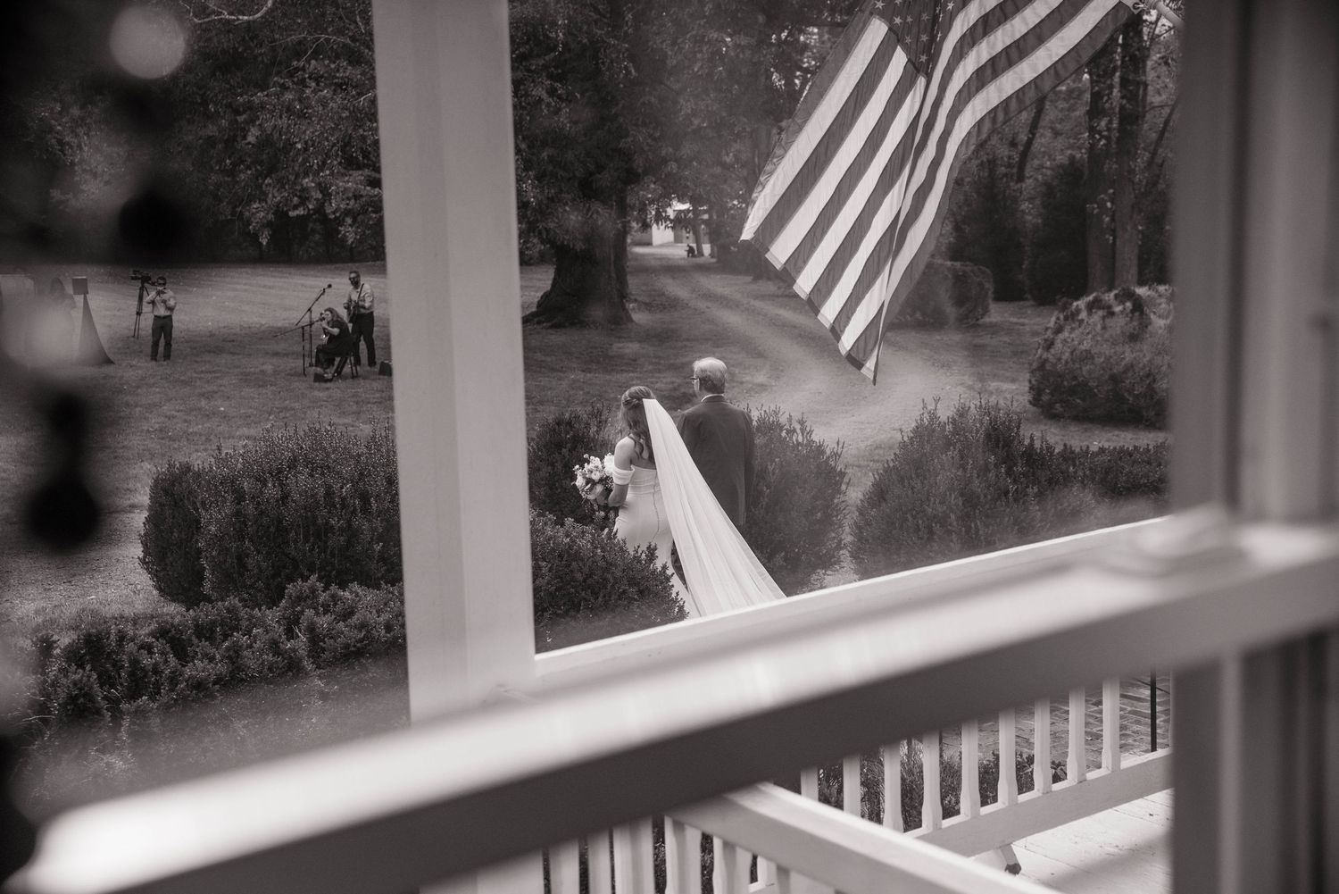 White porch columns with American flags creating a patriotic wedding venue atmosphere.