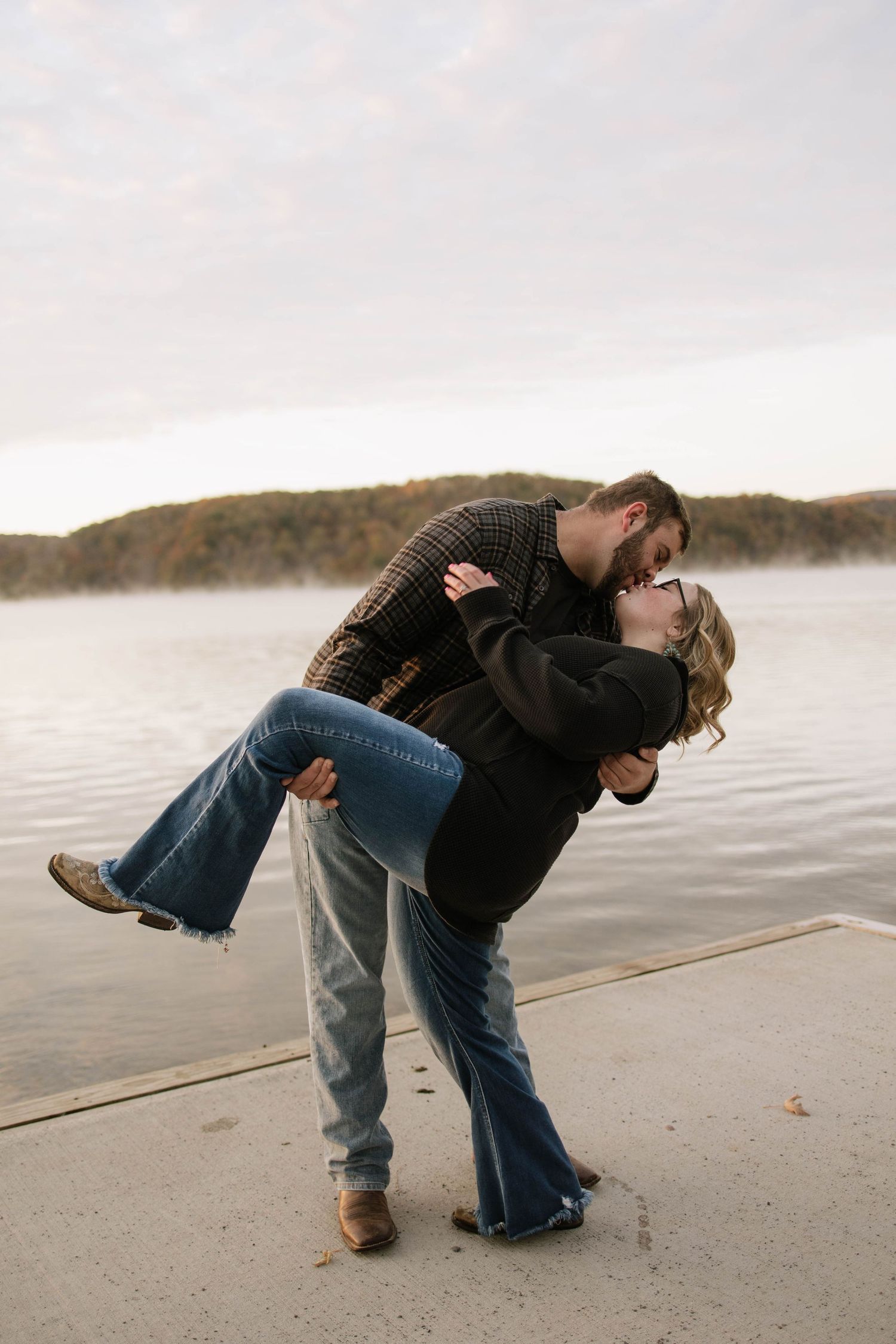 A romantic dip pose between a couple on a lakeside dock.