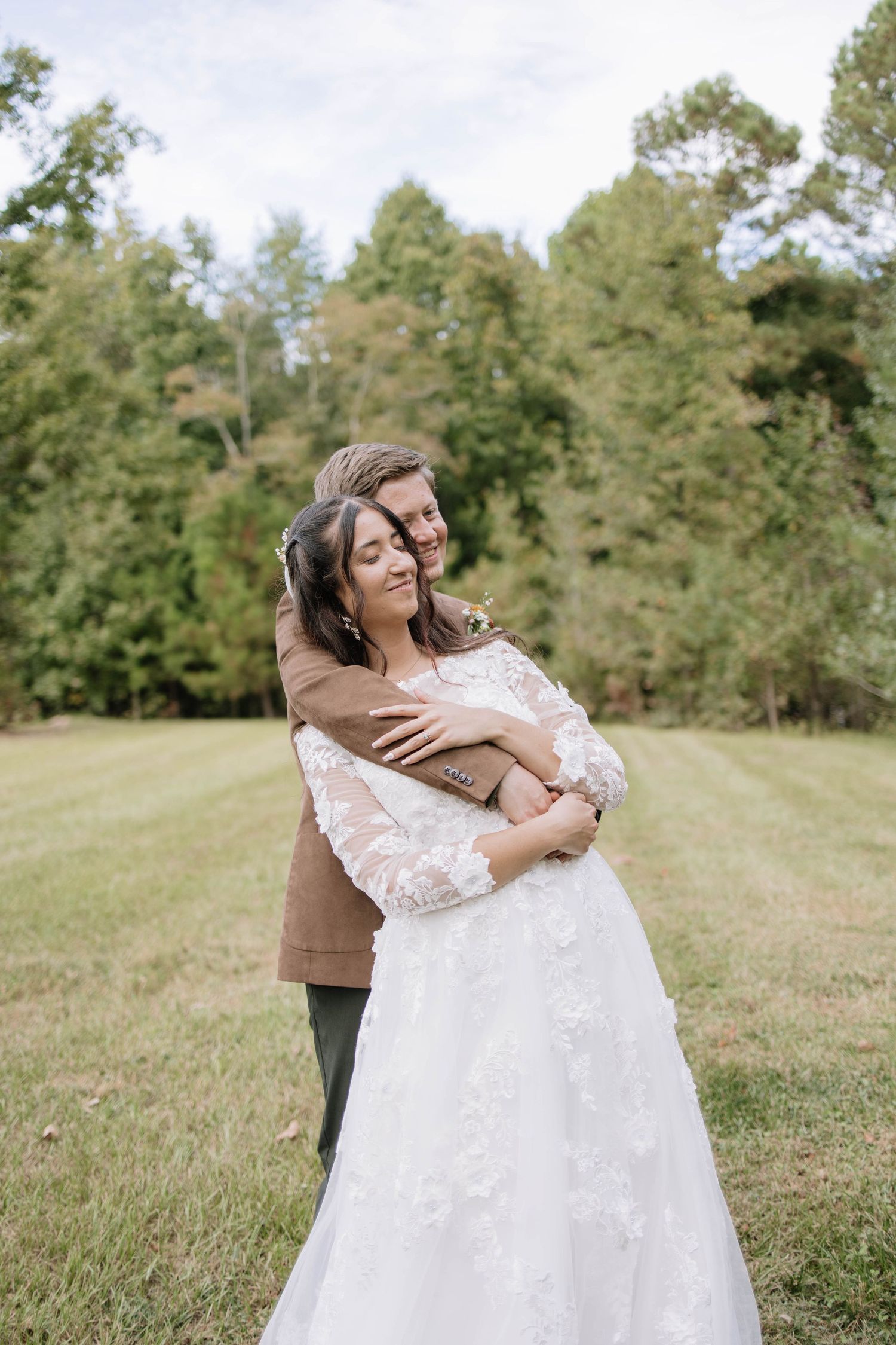 A couple embraces joyfully during their wedding photoshoot in a scenic outdoor setting.