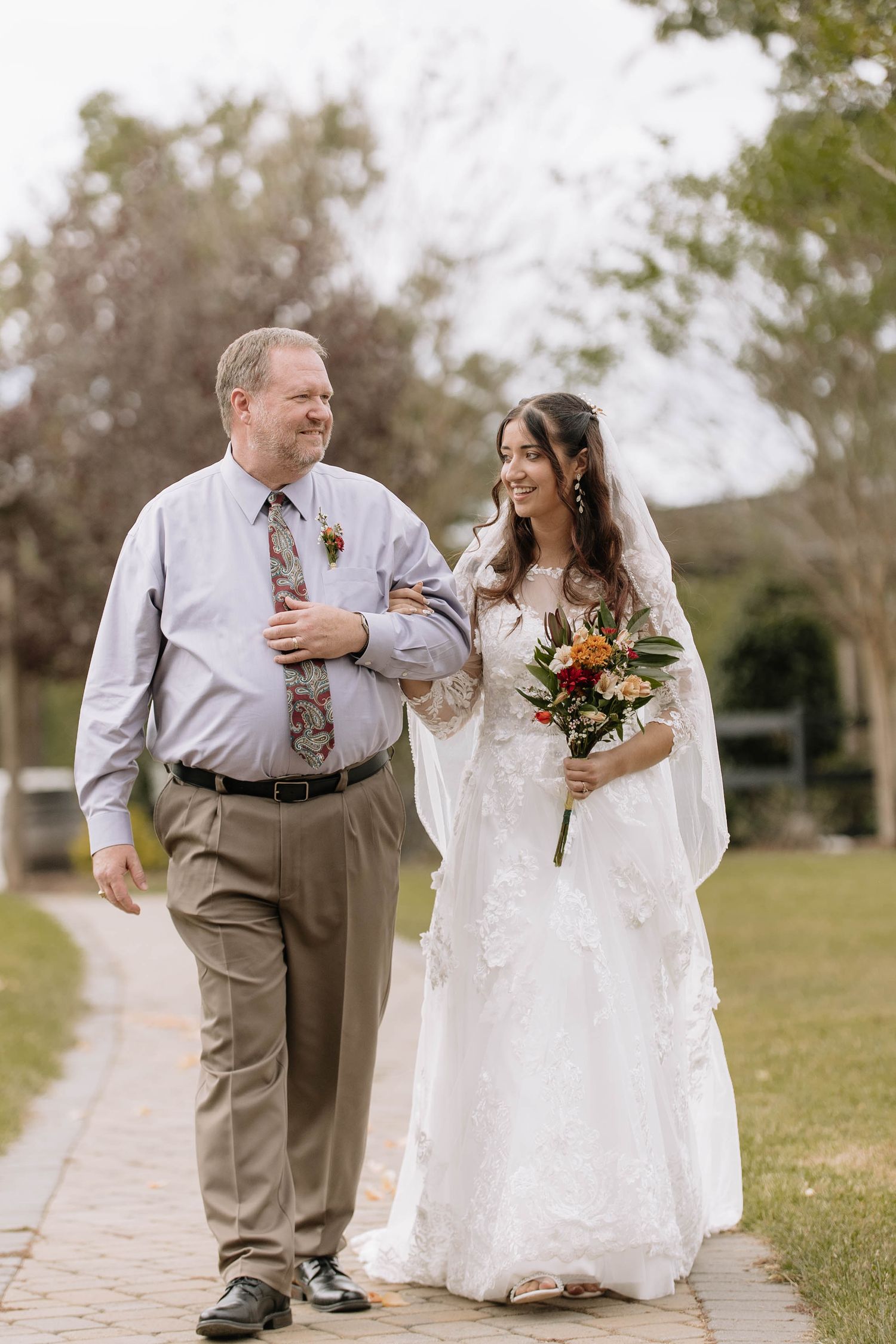Couple walking together on stone path during outdoor wedding celebration.