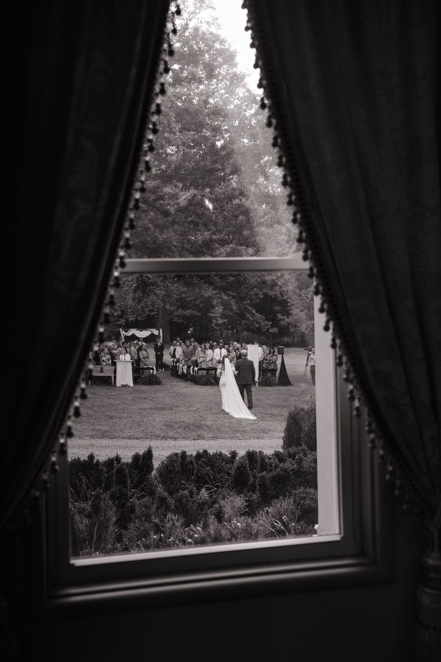 View through dark curtains of an outdoor wedding ceremony space.