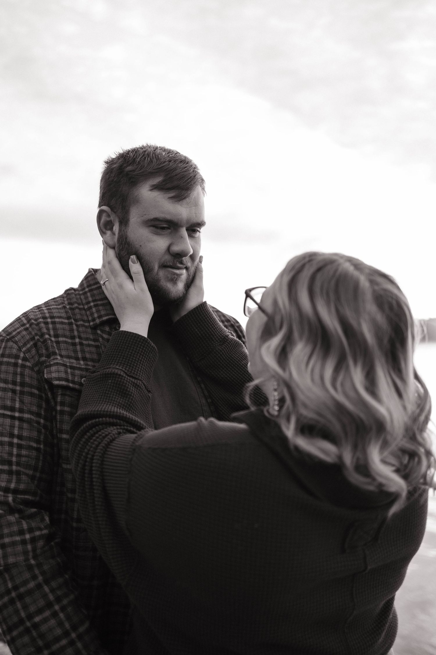 An intimate black and white portrait of a couple by the water.