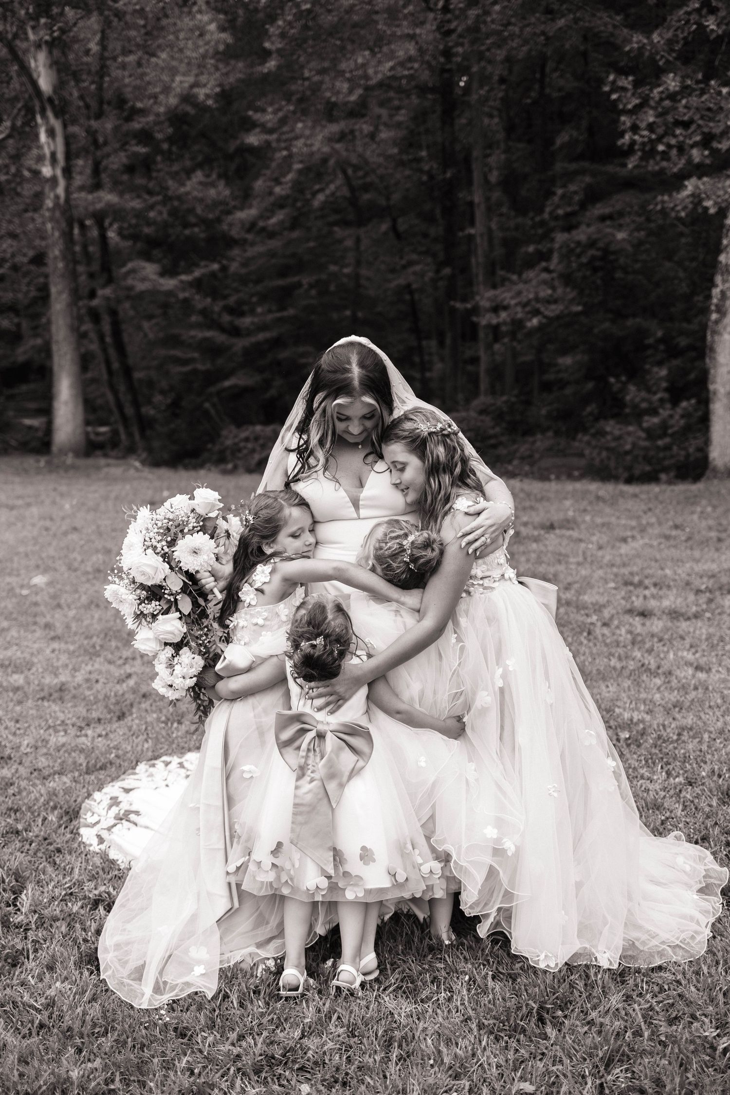 Black and white photo of flower girls in white dresses playing in a grassy field.