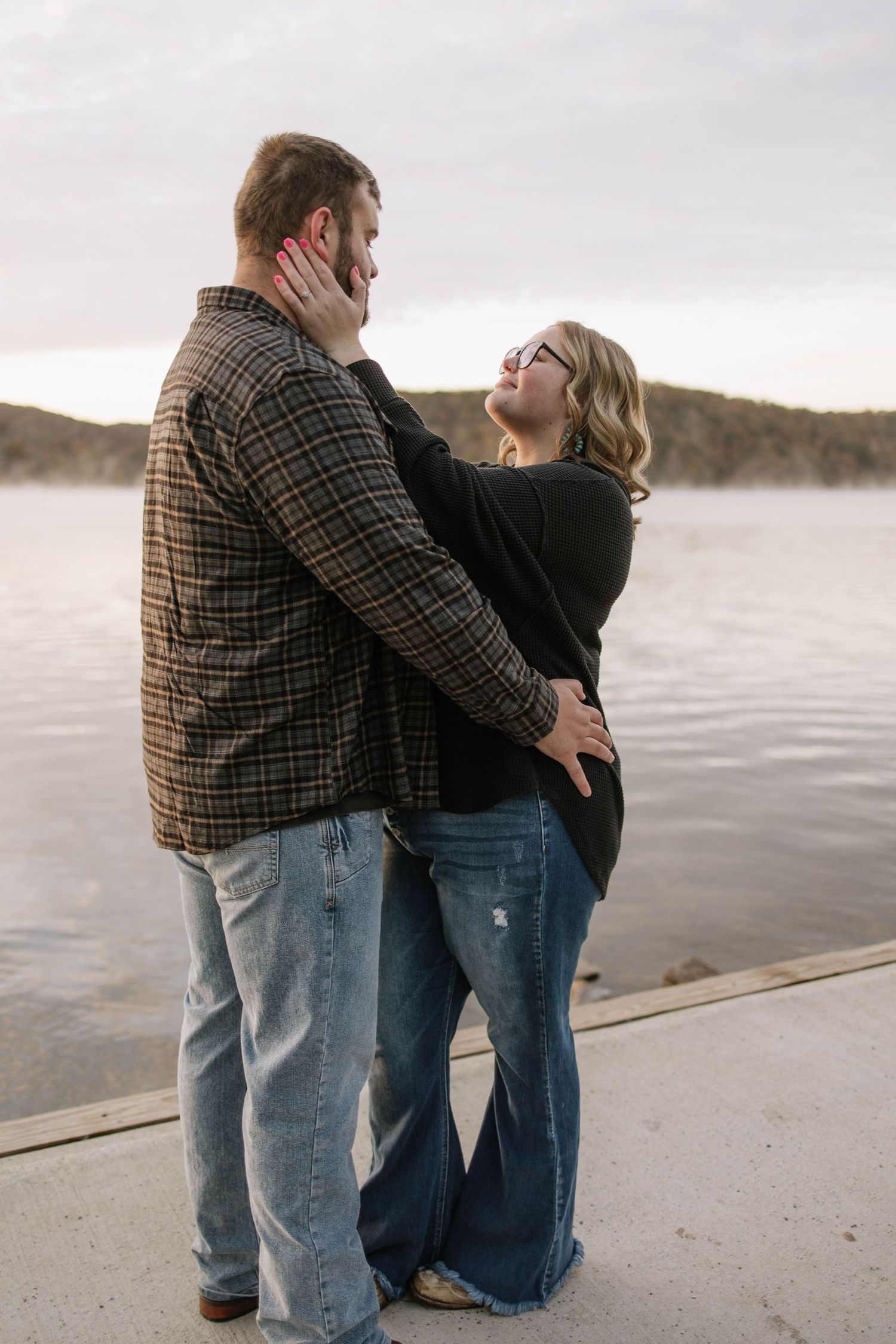 A couple sharing an affectionate moment on a lakeside dock.