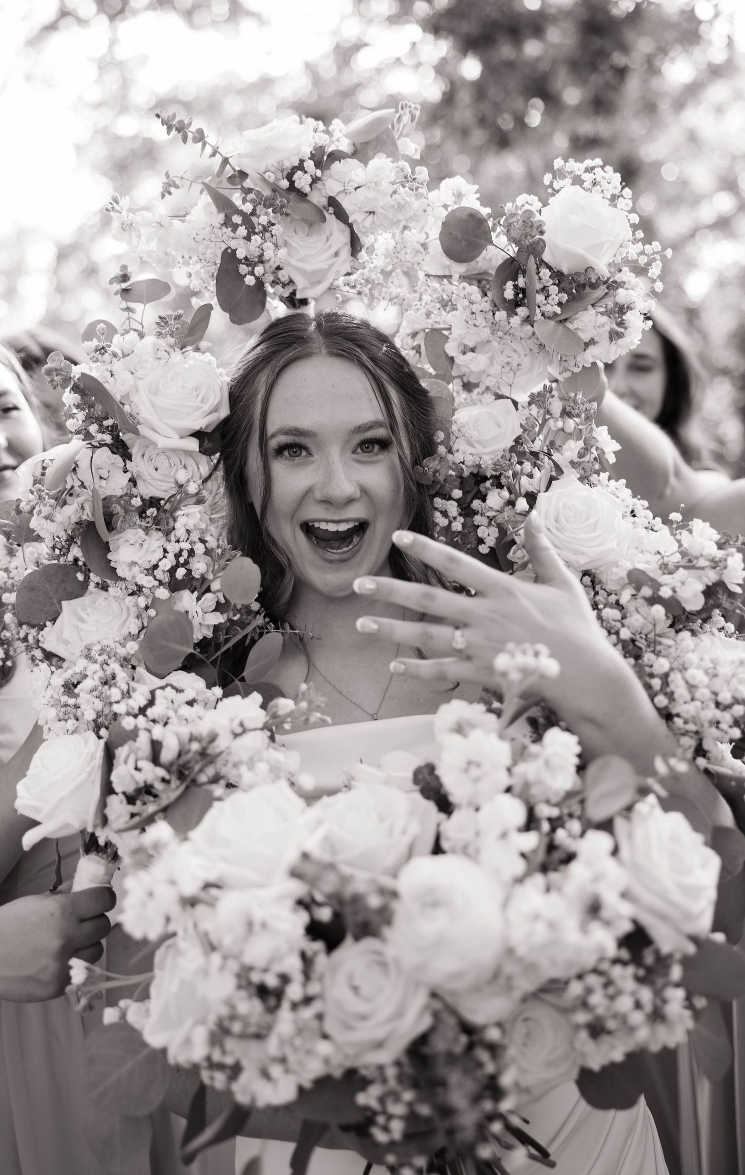 A joyful moment captured in black and white among delicate spring blossoms and elegant white roses.