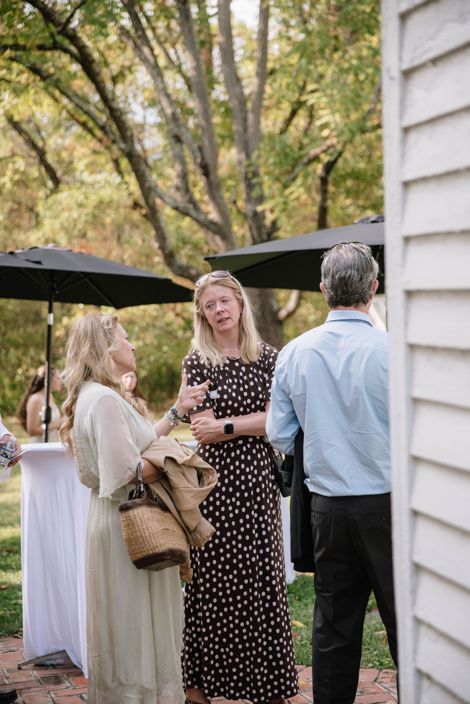 Wedding guests gathering outdoors near a white building during a reception.