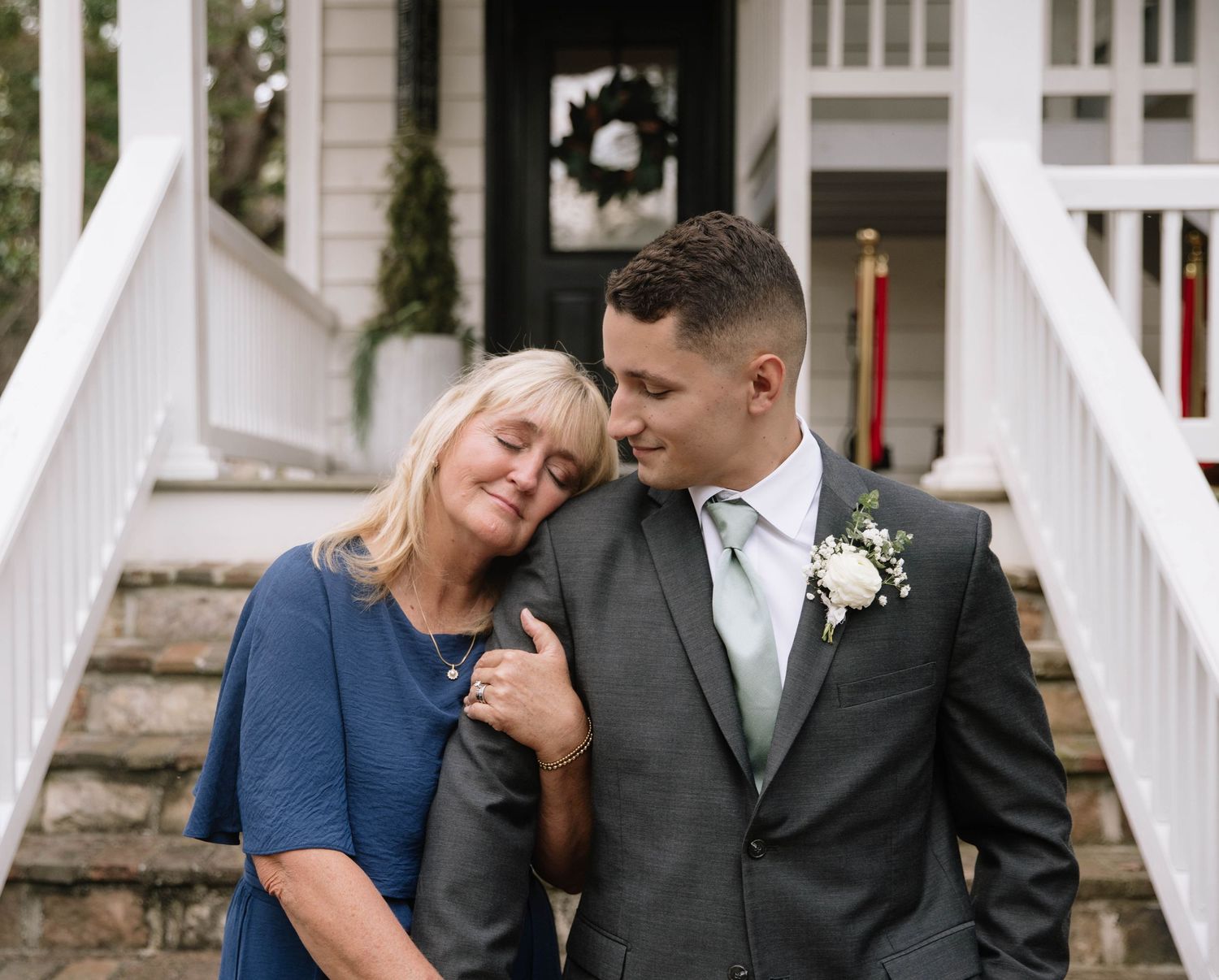 A tender moment captured on white porch steps during a wedding day.