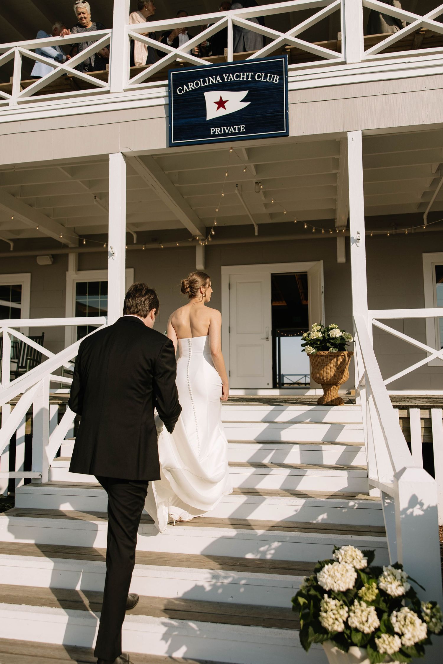 Bride and groom walking up steps at Carolina Yacht Club for their elegant waterfront wedding ceremony.