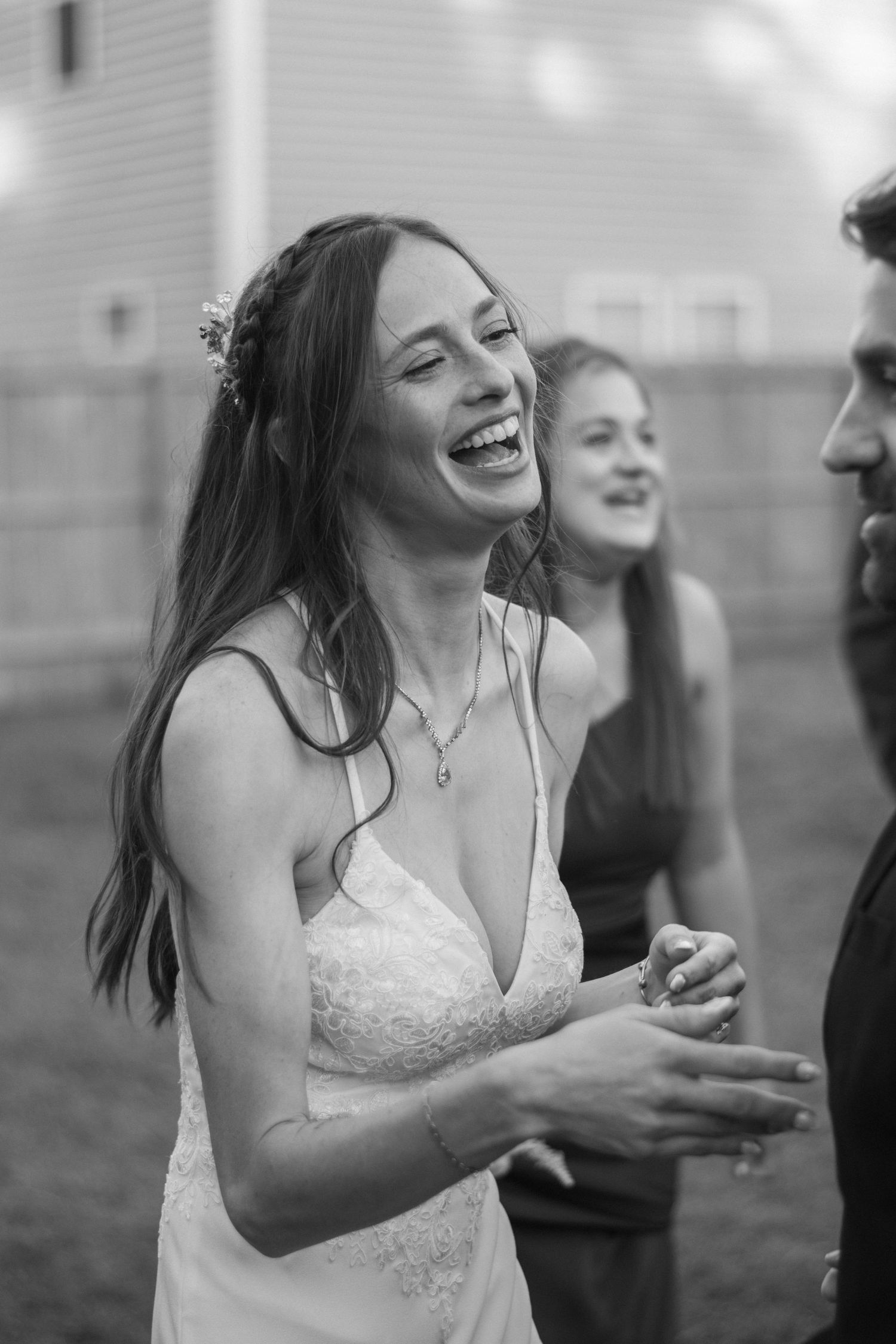 A series of black and white photos showing a bride in a lace dress laughing joyfully during an outdoor celebration.
