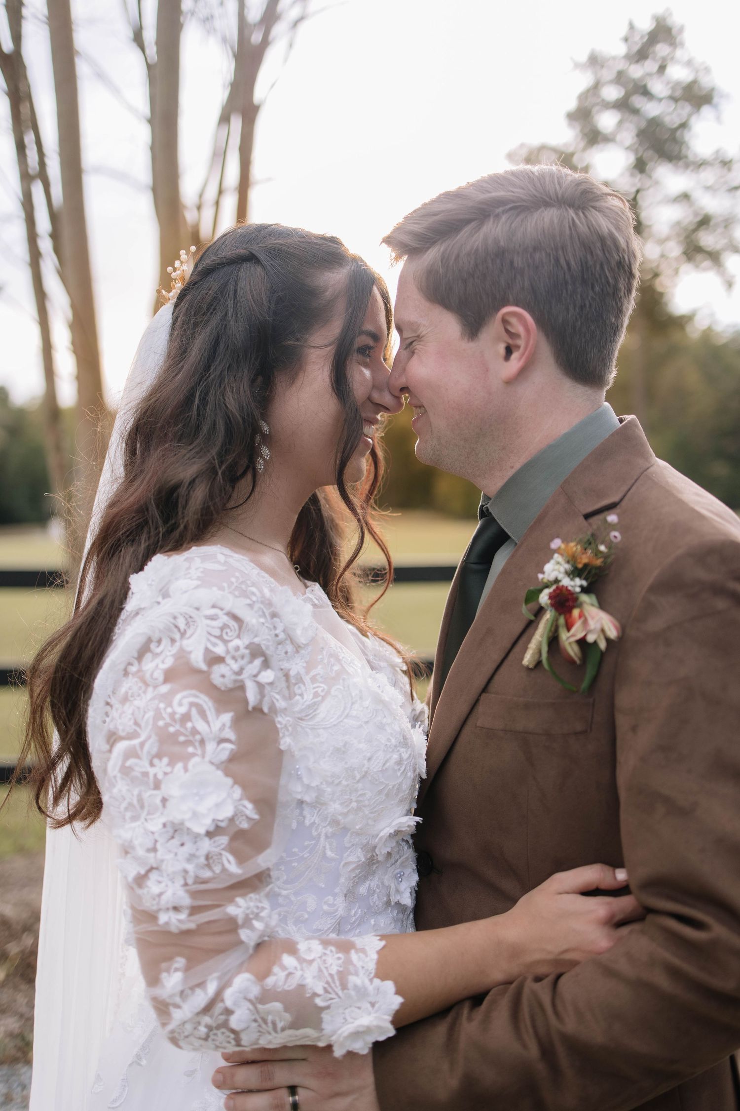 Intimate wedding portrait with couple sharing a tender moment against natural backdrop.