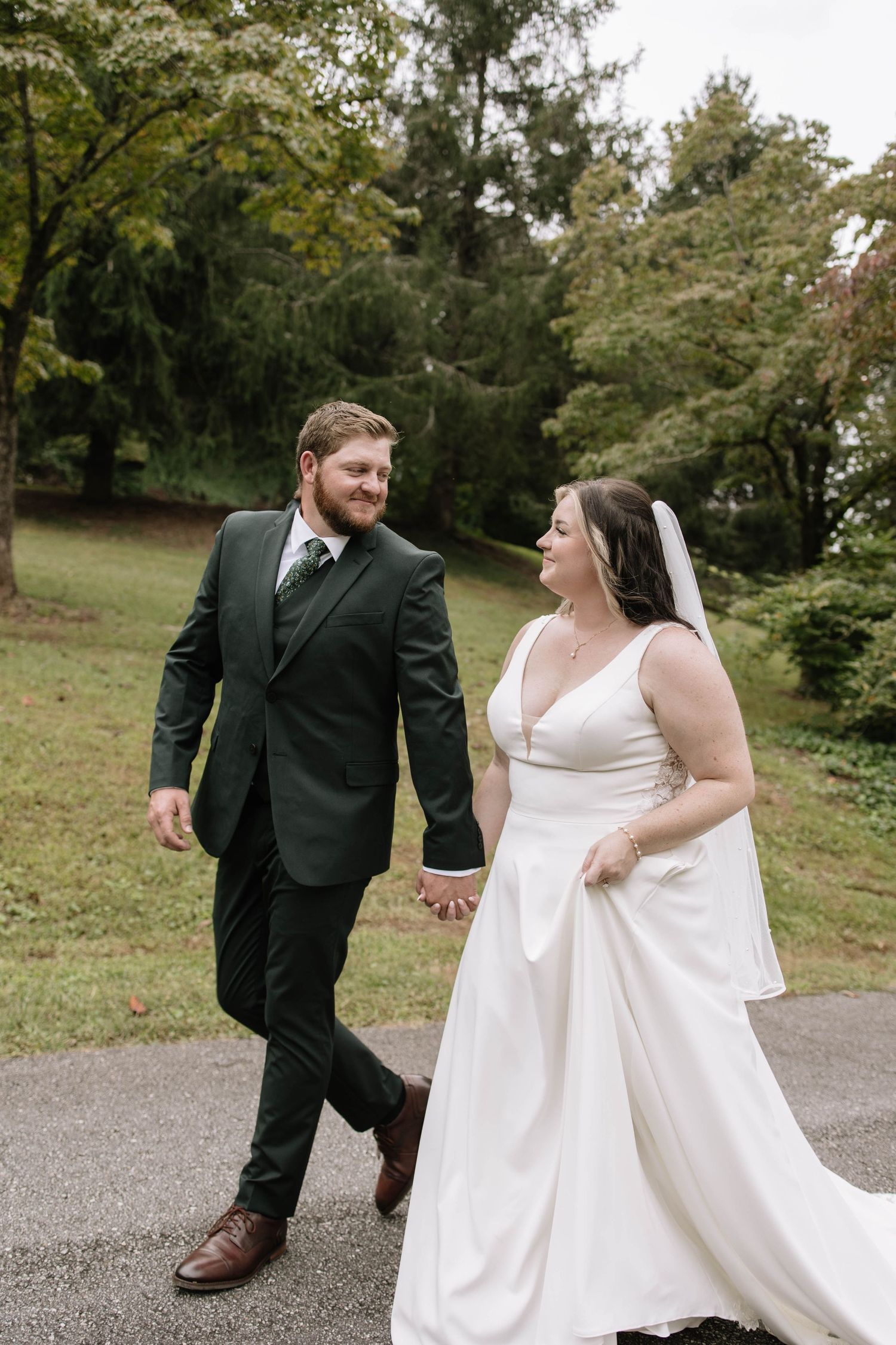 Playful wedding portraits showing couple walking and dancing on gravel path.