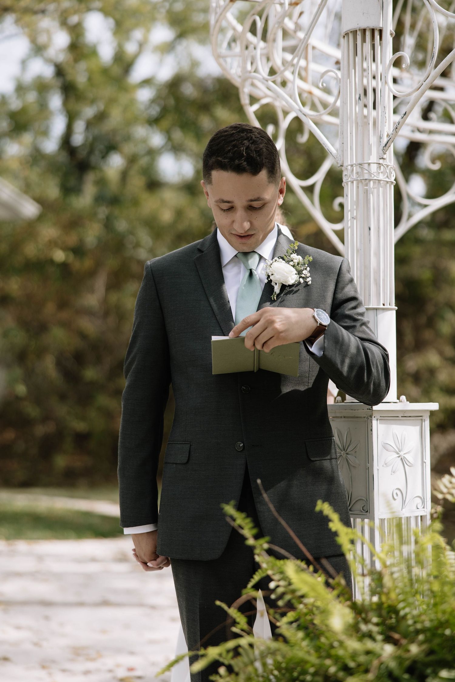 Wedding couple holds hands while standing beneath an elegant white gazebo structure.
